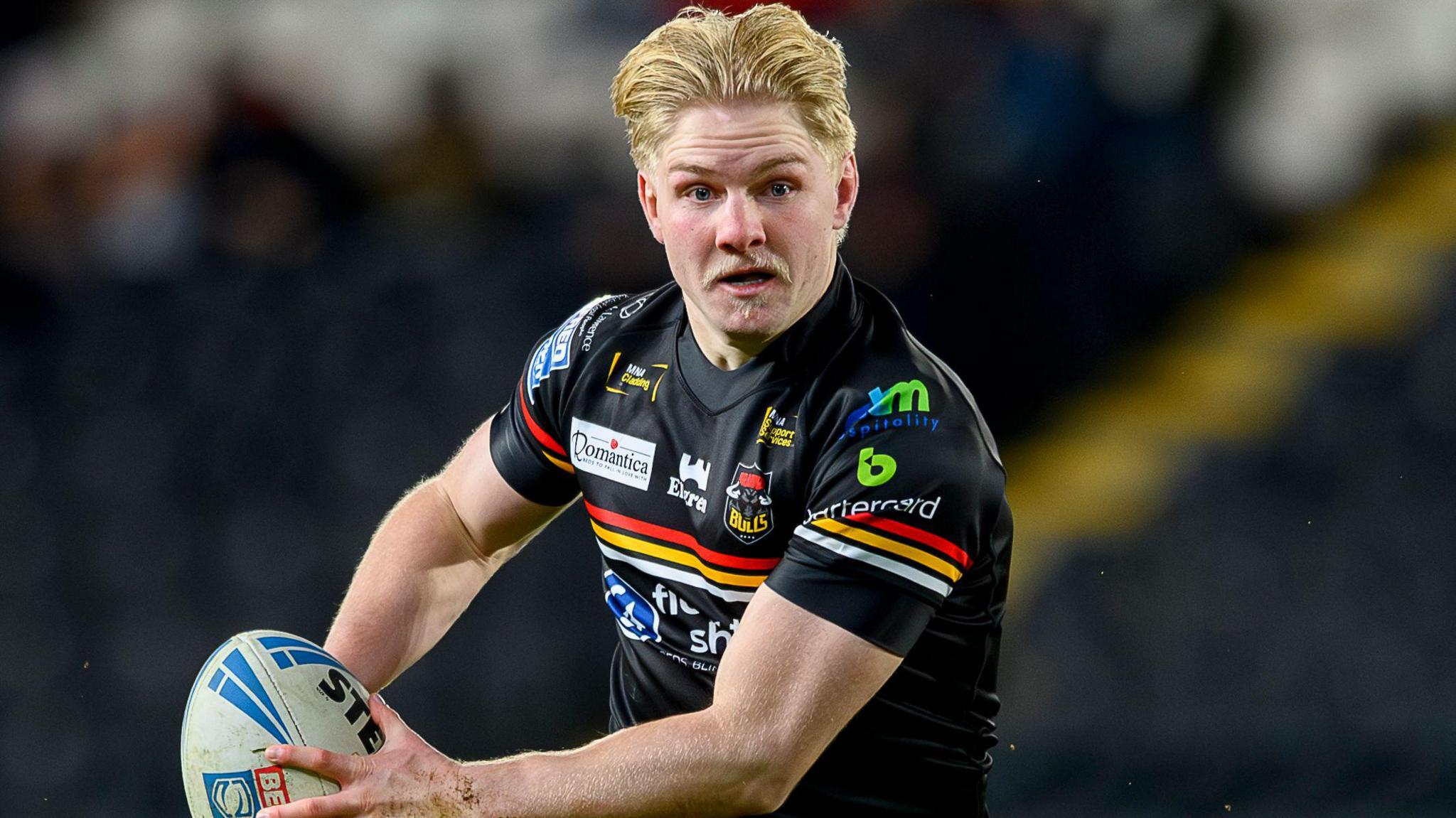 Mitch Souter, wearing the black Bradford Bulls shirt, runs with the ball in both hands in a game against Hull FC