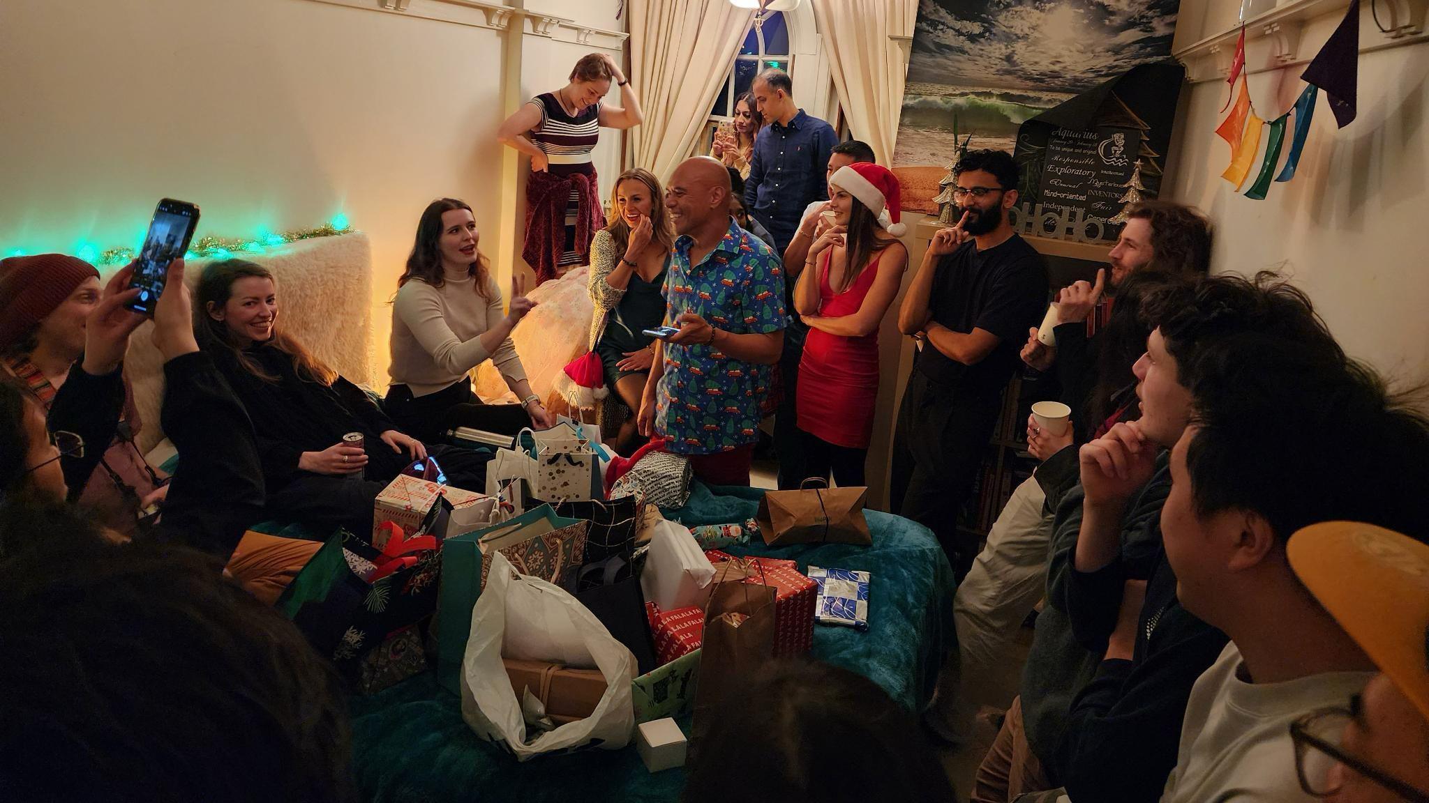 A group of people stand around a pile of presents