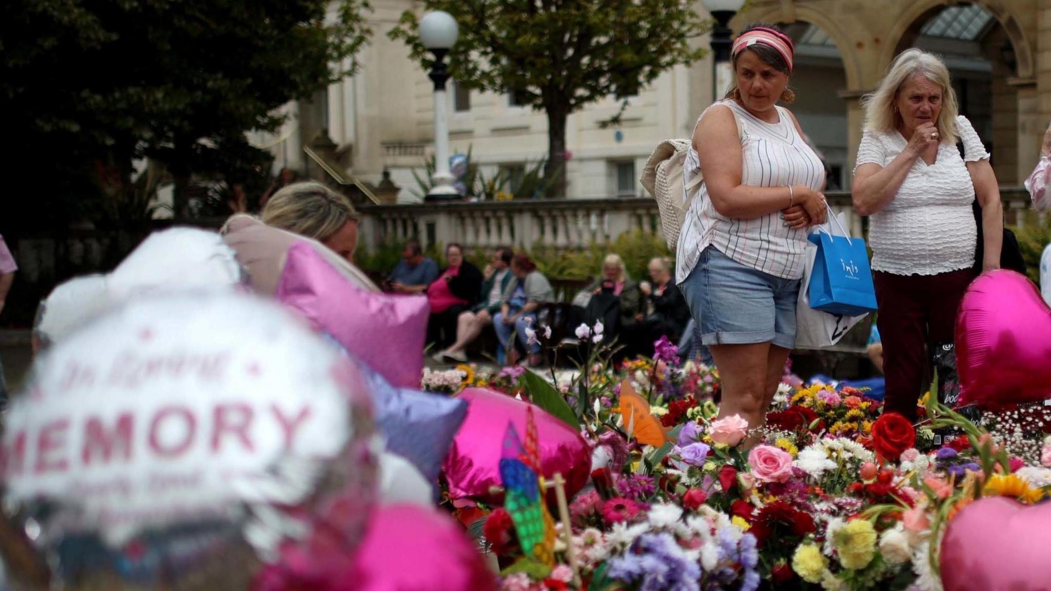 Two women look at the floral tributes and balloons left in memory of the victims of the Stourport stabbing attack