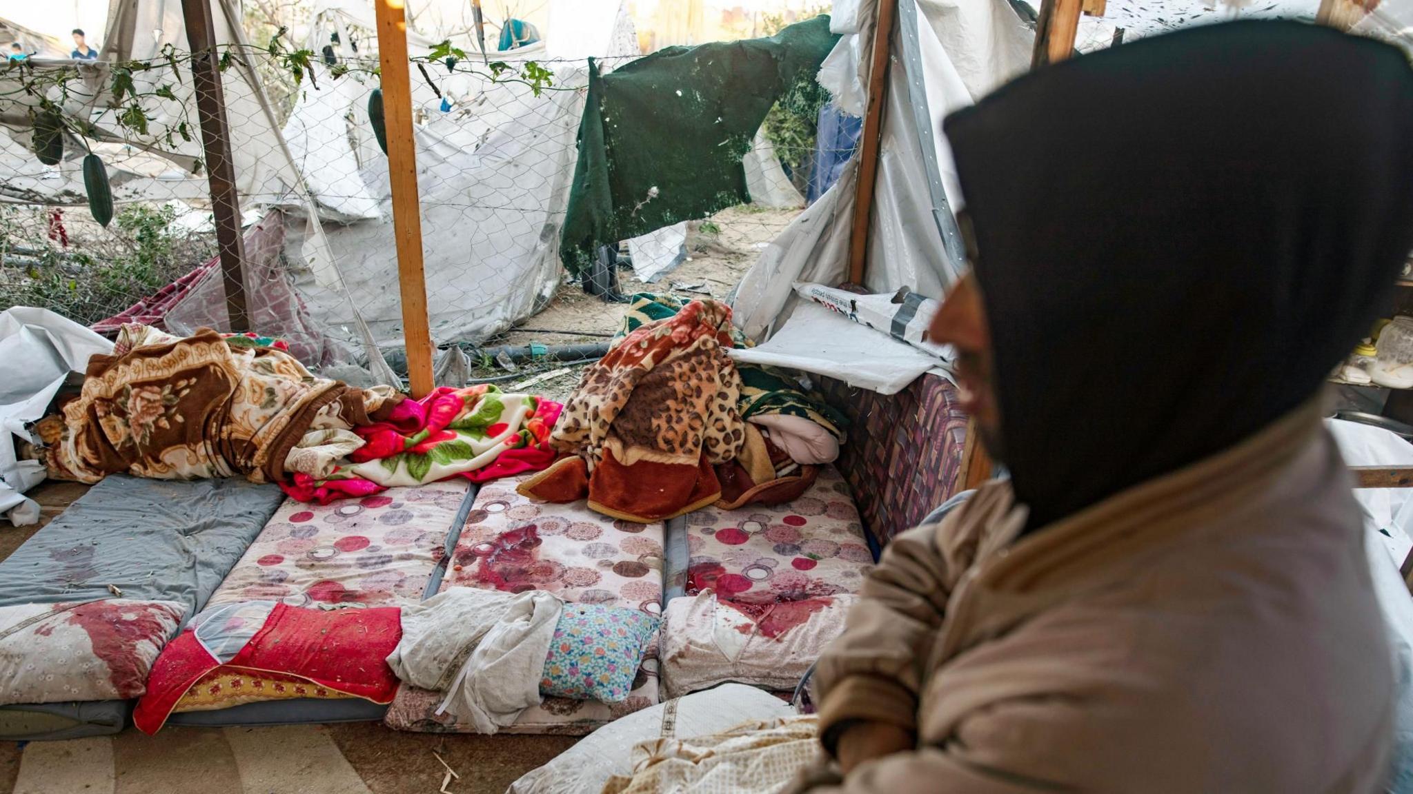 A Palestinian man stands near the blood-stained mattresses where Ahmed, Mohammed and Abdul Rahman al-Bardawil were killed in an Israeli strike, in al-Mawasi, southern Gaza (2 January 2025)