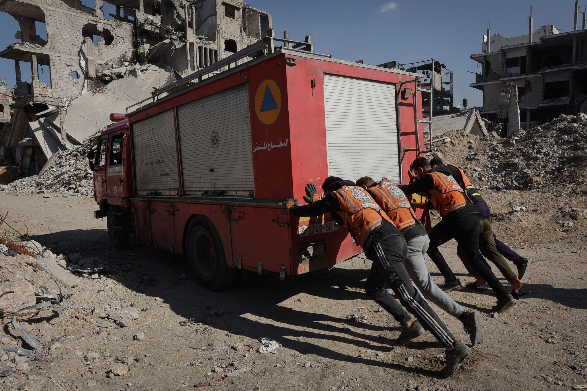 Civil Defence rescuers push a fire truck amid destruction in the Shujaiyah neighbourhood in Gaza City in November.