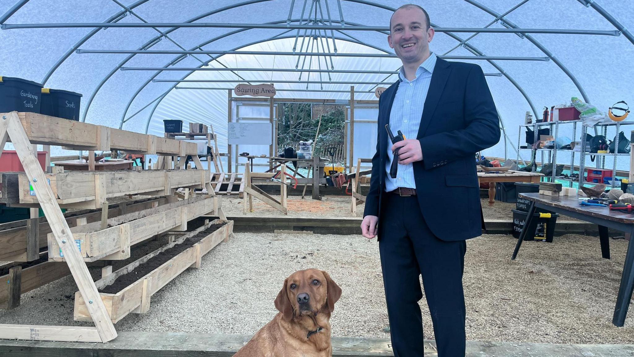 Headteacher Dan Crossman and the school's therapy dog Woody, standing in the school's forest school