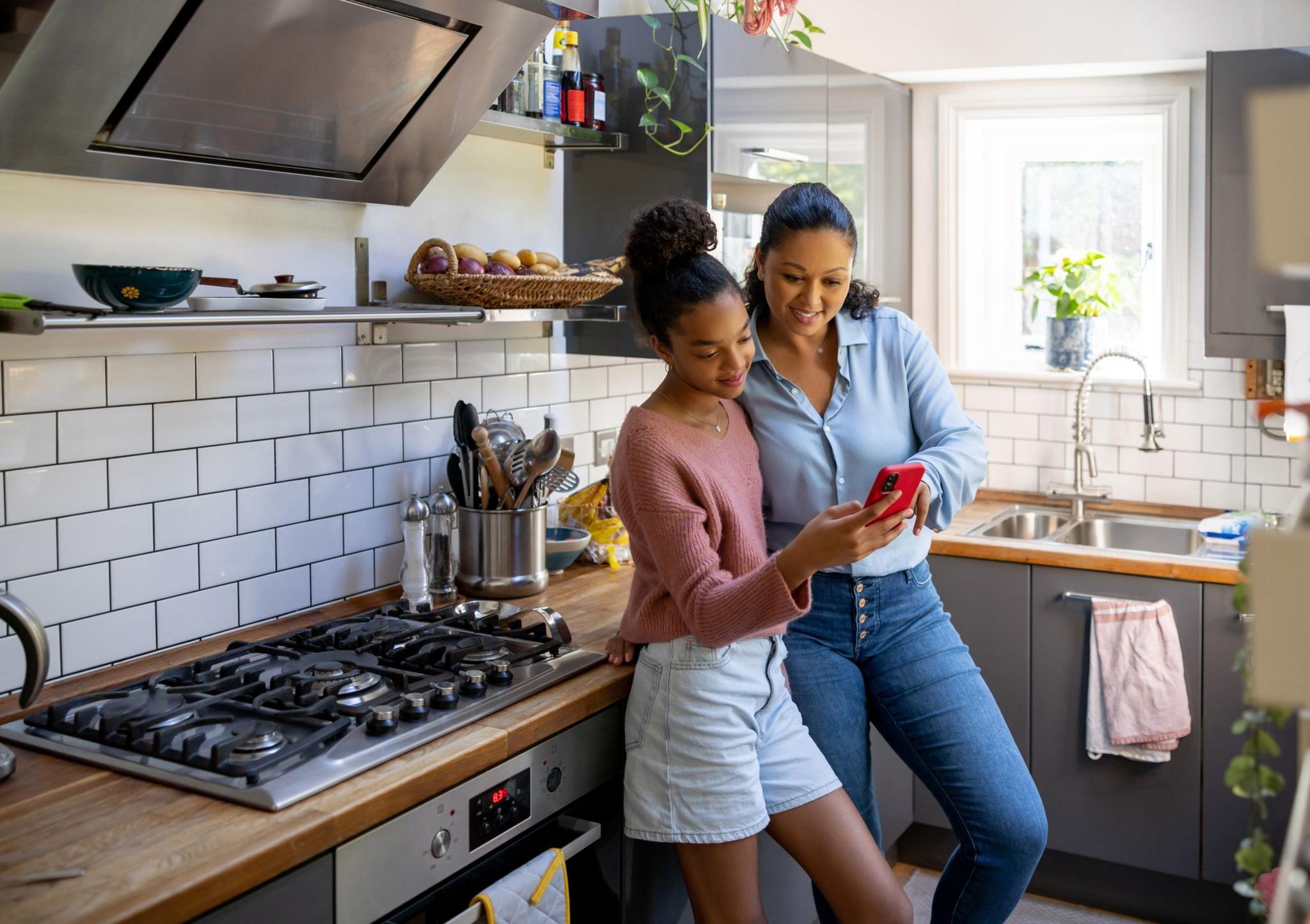 Teenager and mother in kitchen looking at a phone