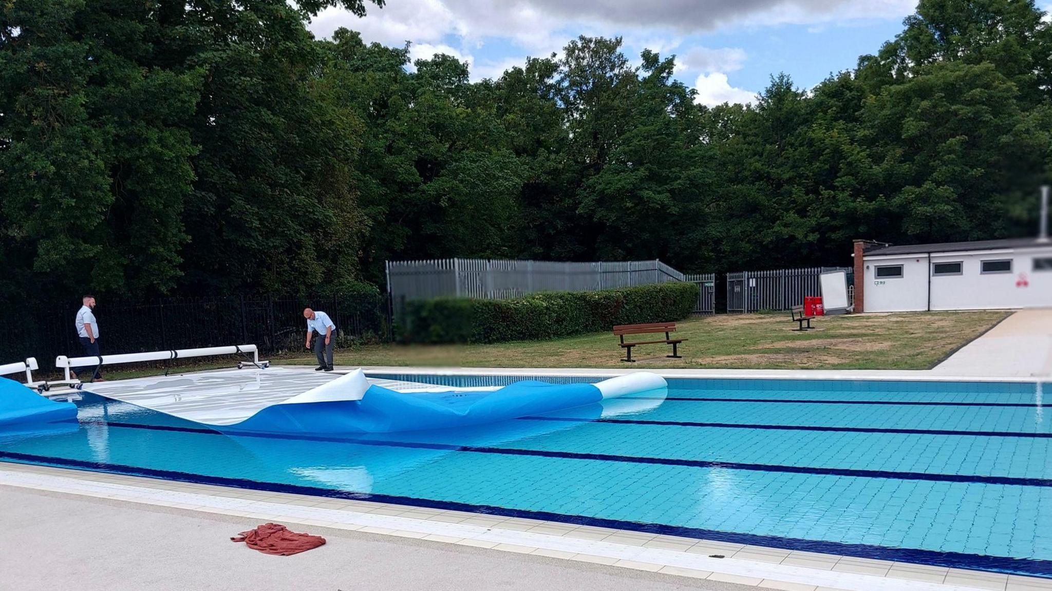 Two men handling the covers of Abbey Pool.