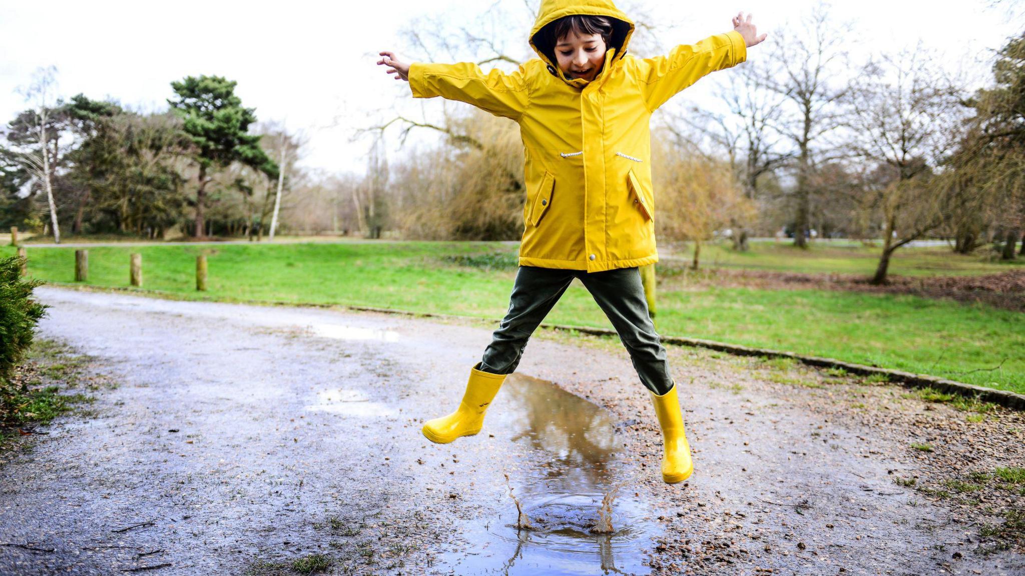 Boy jumping in puddle. 