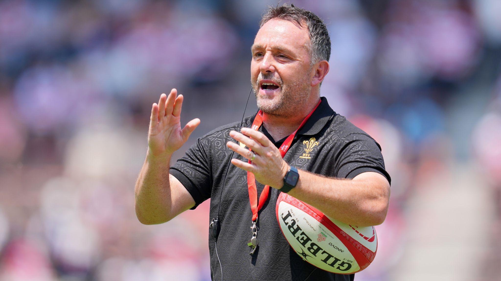 Matt Sherratt gestures with his hands while holding a rugby ball