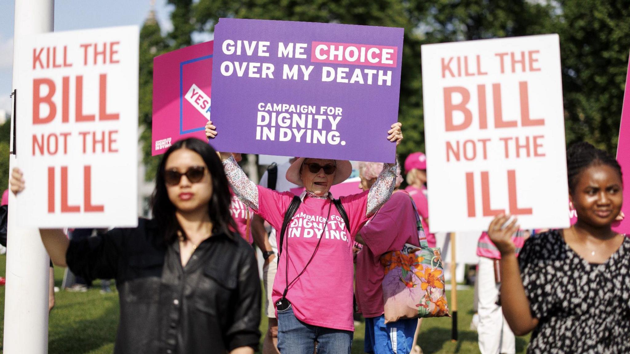 Campaigners for and against assisted dying hold placards outside Parliament reading "kill the bill not the ill" and "give me choice over my death".