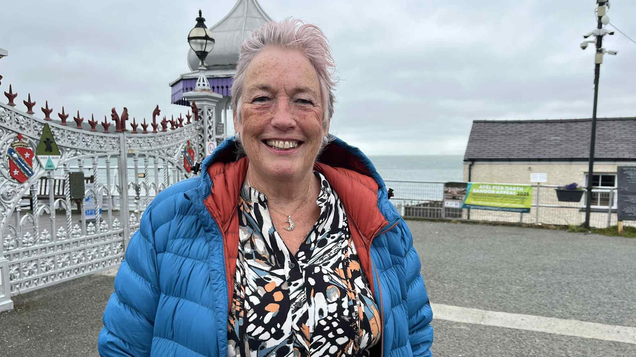 Avril Wayte yn sefyll ger y pier