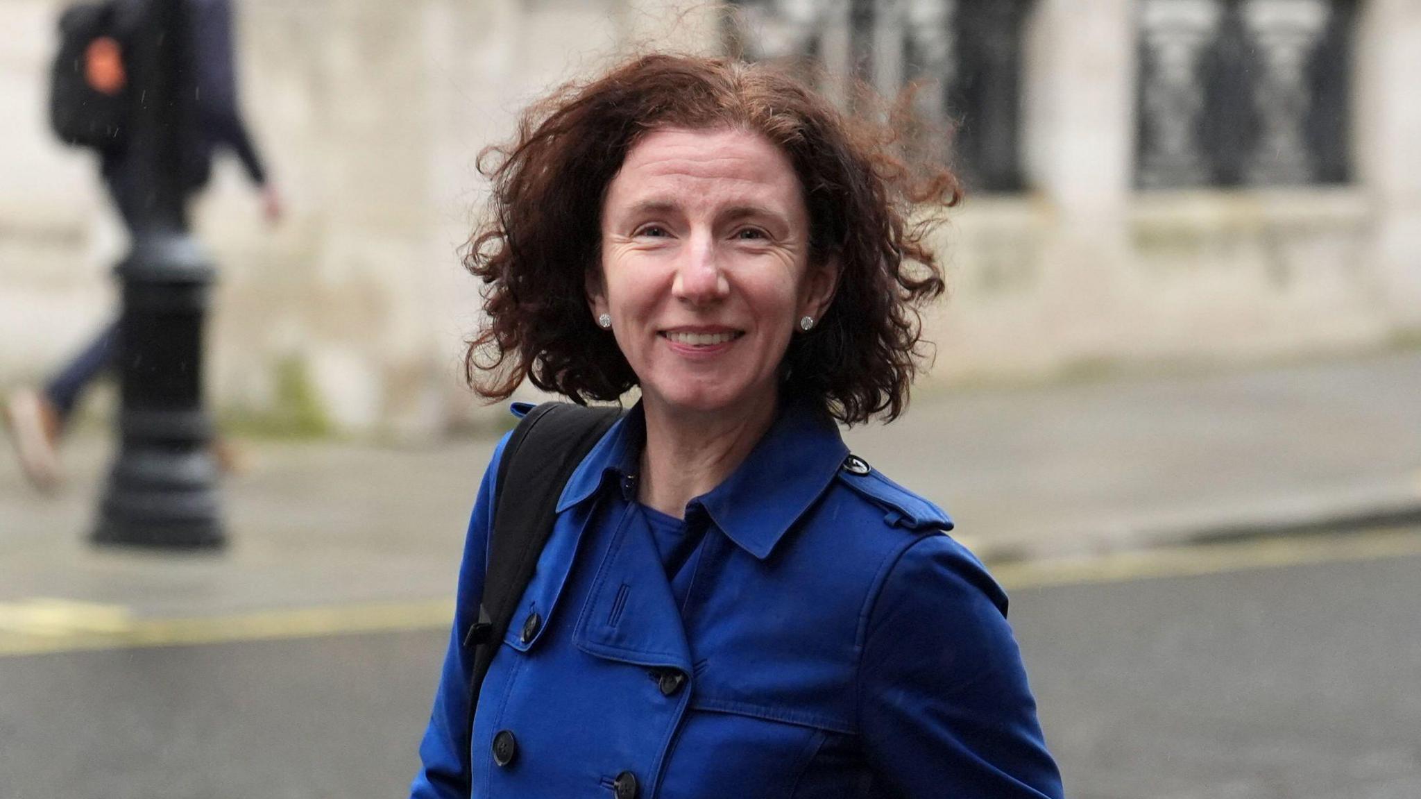 Anneliese Dodds has medium length dark hair and is wearing a blue mac rain coat.