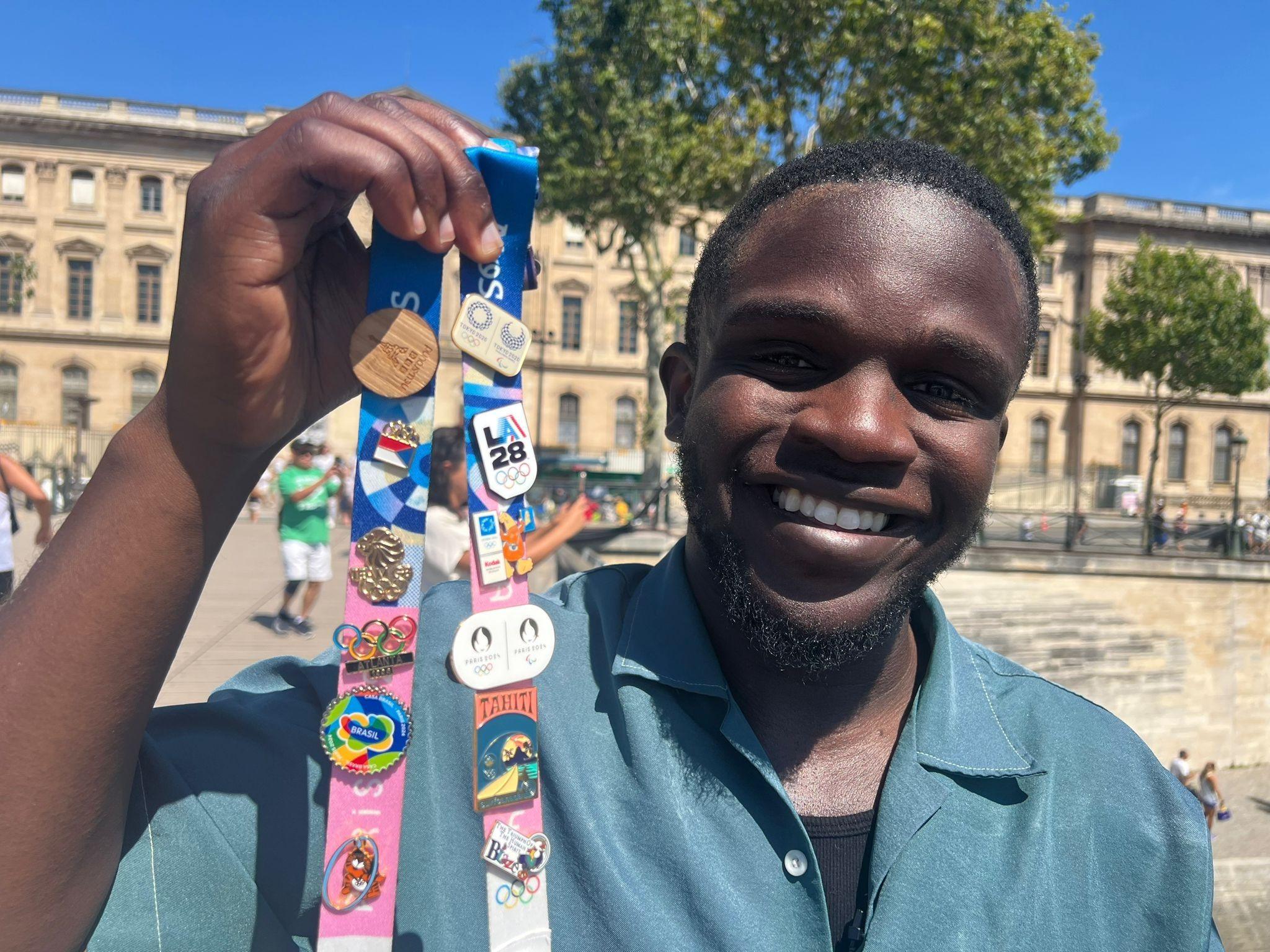 De-Graft Mensah holding his Olympic pins. 