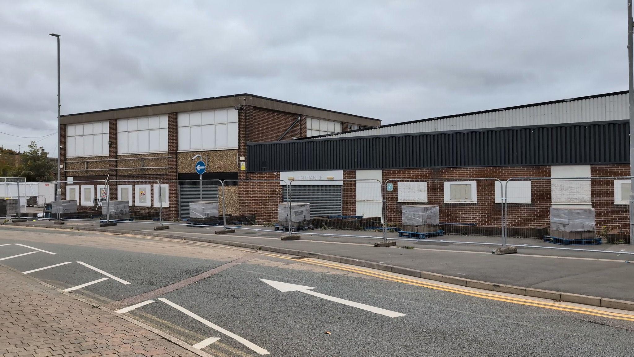 A former factory shop is pictured with metal fencing surrounding it