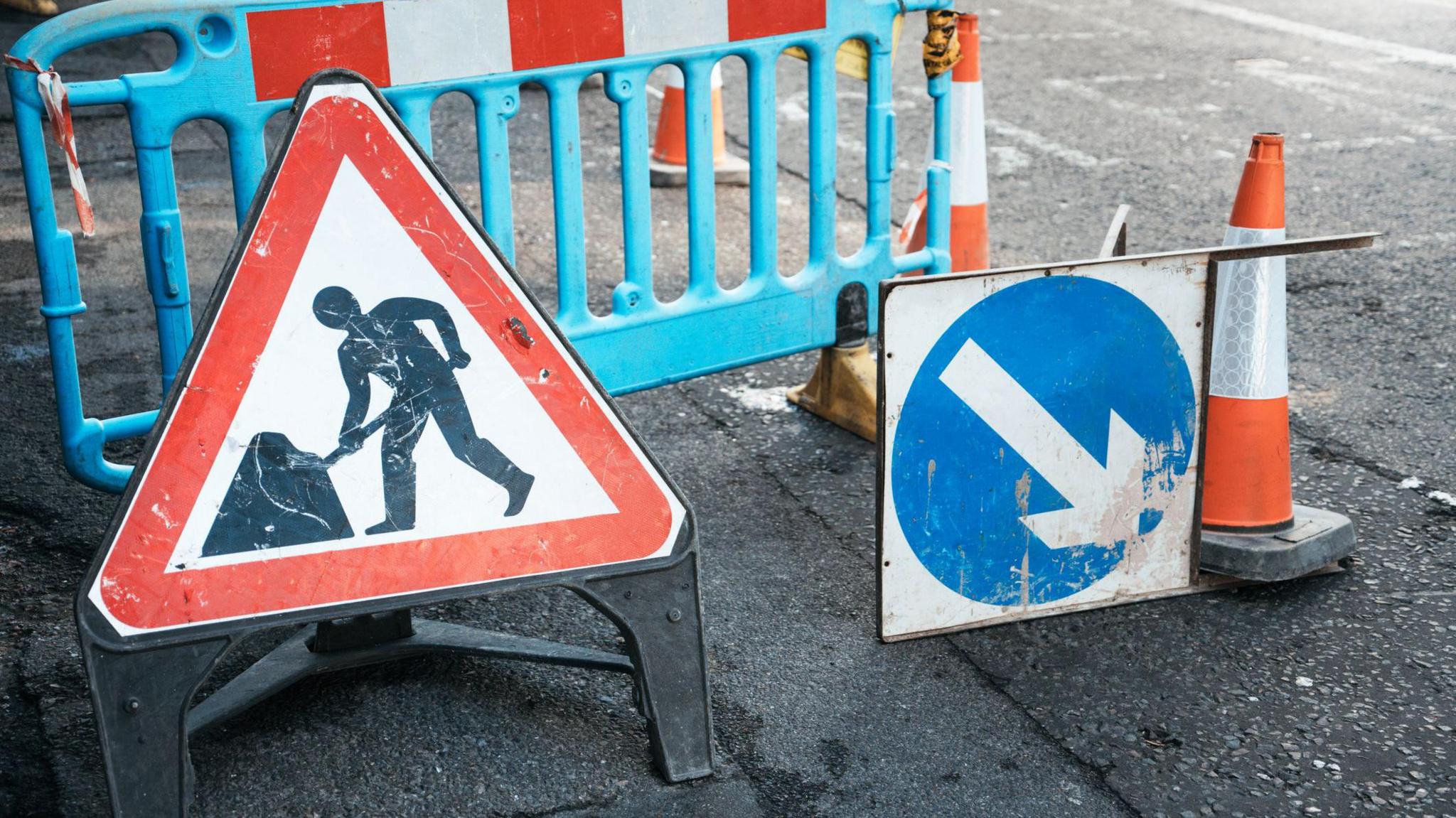 Under construction board sign on the closed road with arrow sign and traffic cone. Caution symbol under construction, work in progress sign. - stock photo