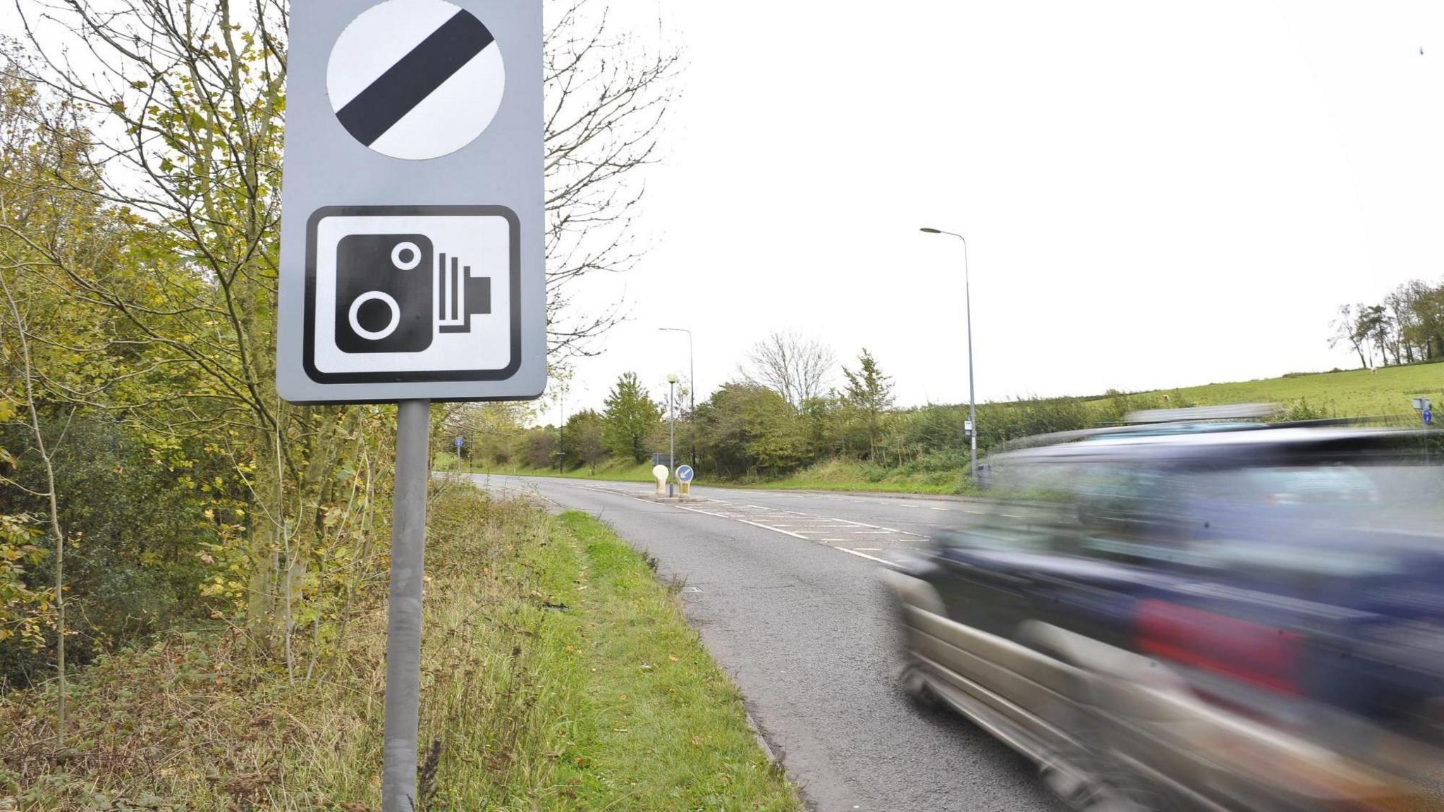 A speed camera sign on a rural road.