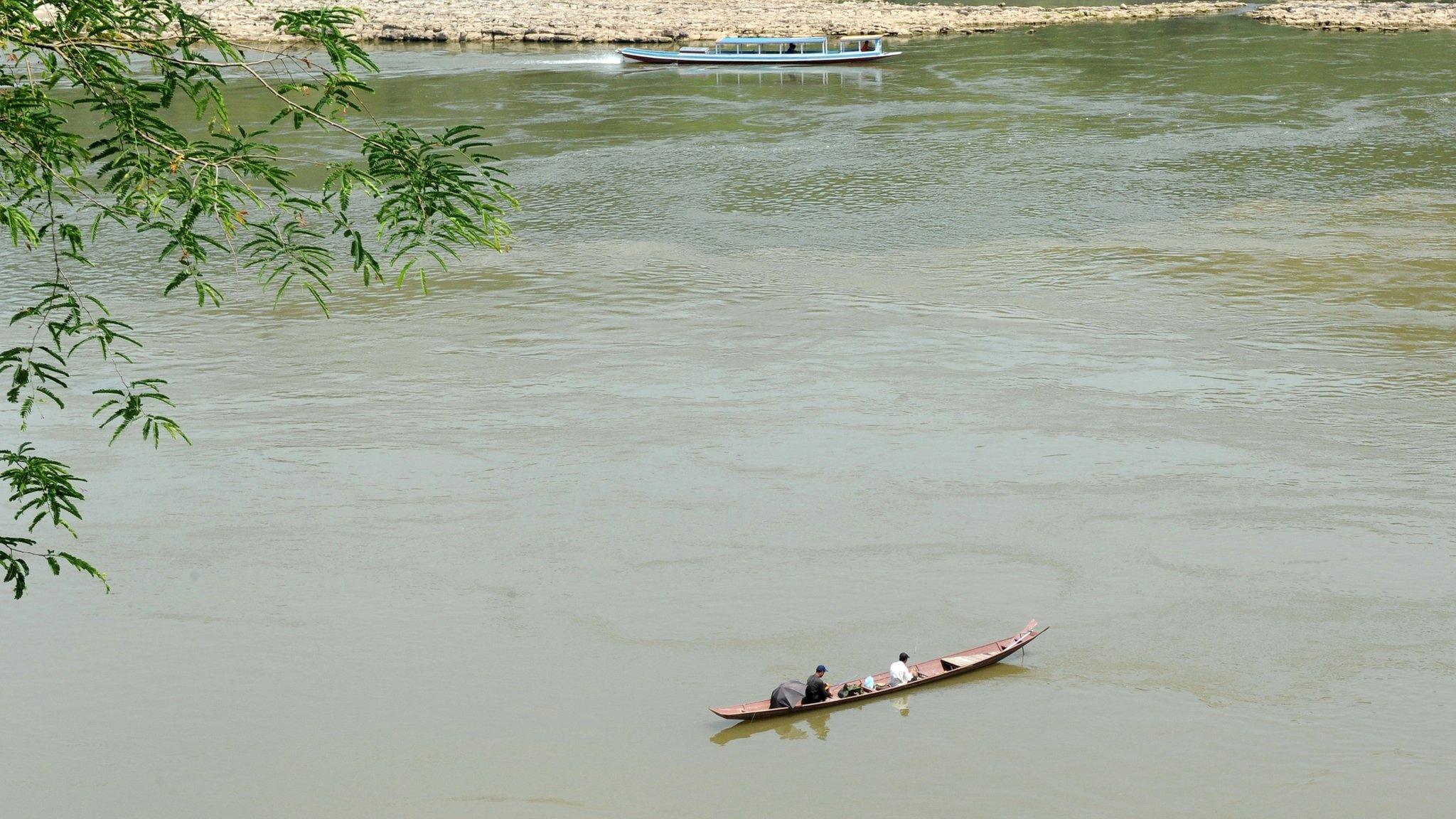 Laotian men fish from their boat in the Mekong river in Luang Prabang