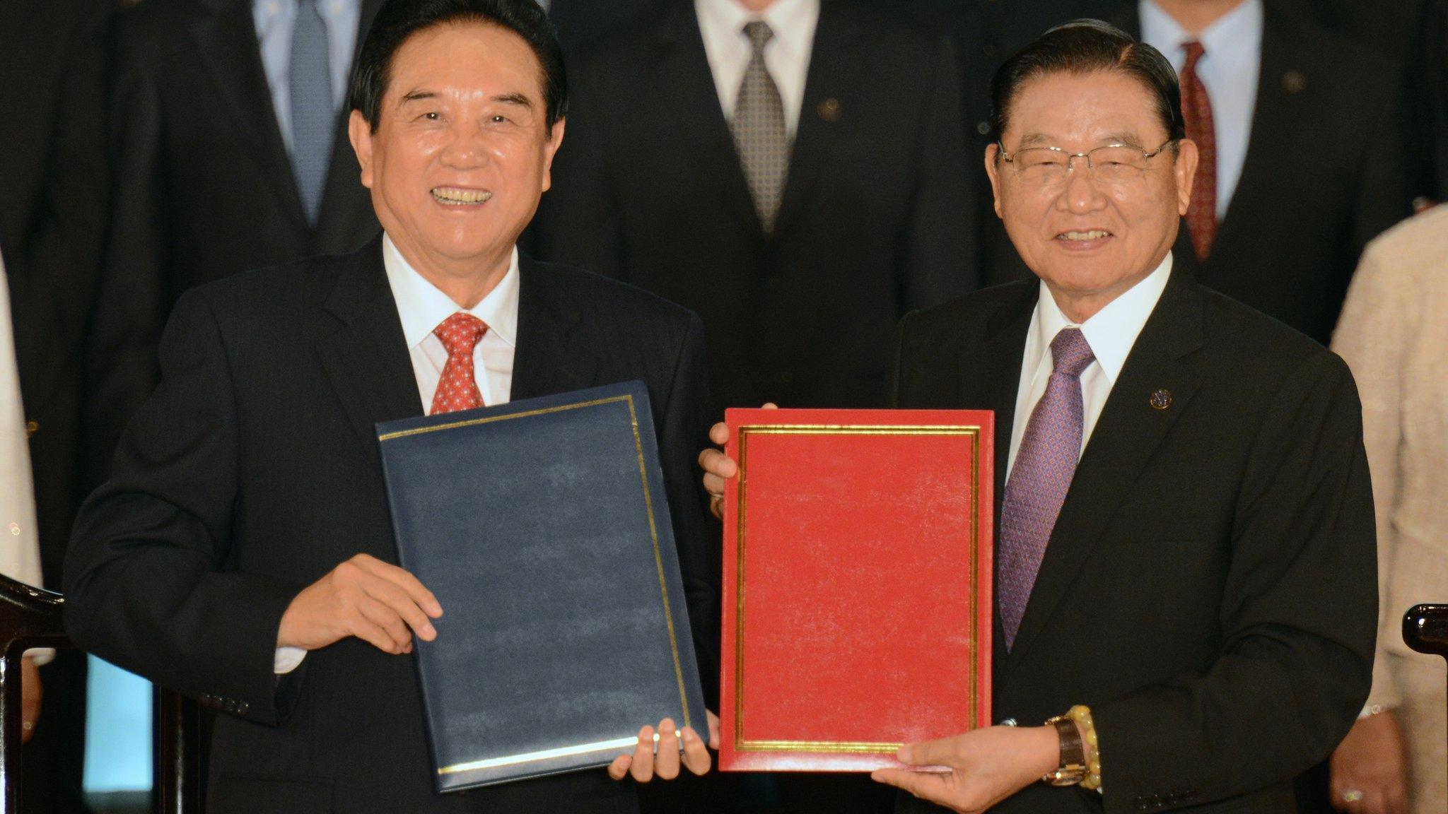 China's chief negotiator Chen Yunlin displays documents with his Taiwanese counterpart Chiang Pin-kung