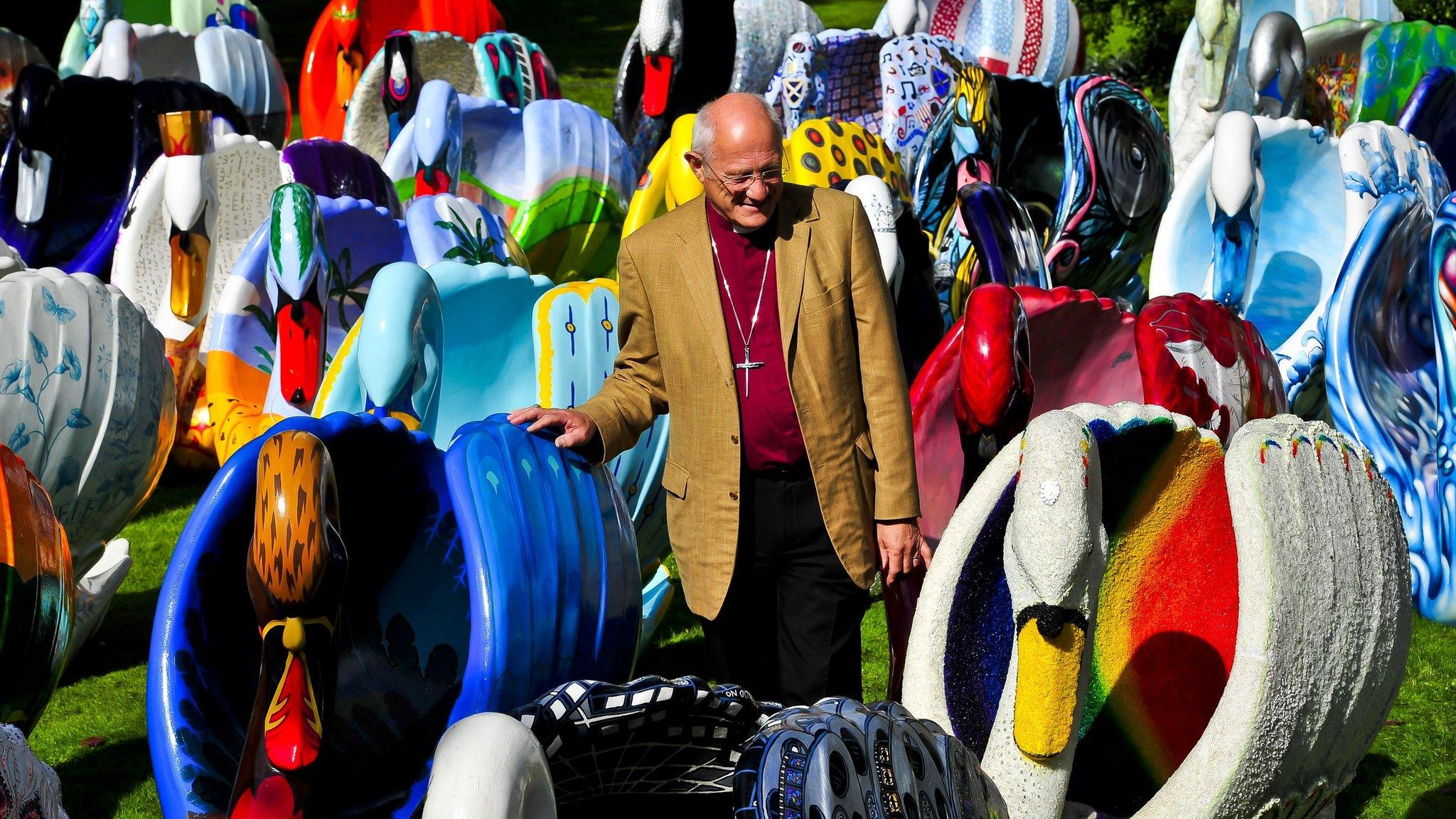 The Bishop of Bath and Wells, Peter Price, checks out the giant flock of around 60 brightly coloured swan sculptures in the grounds of the Bishops Palace, Wells.