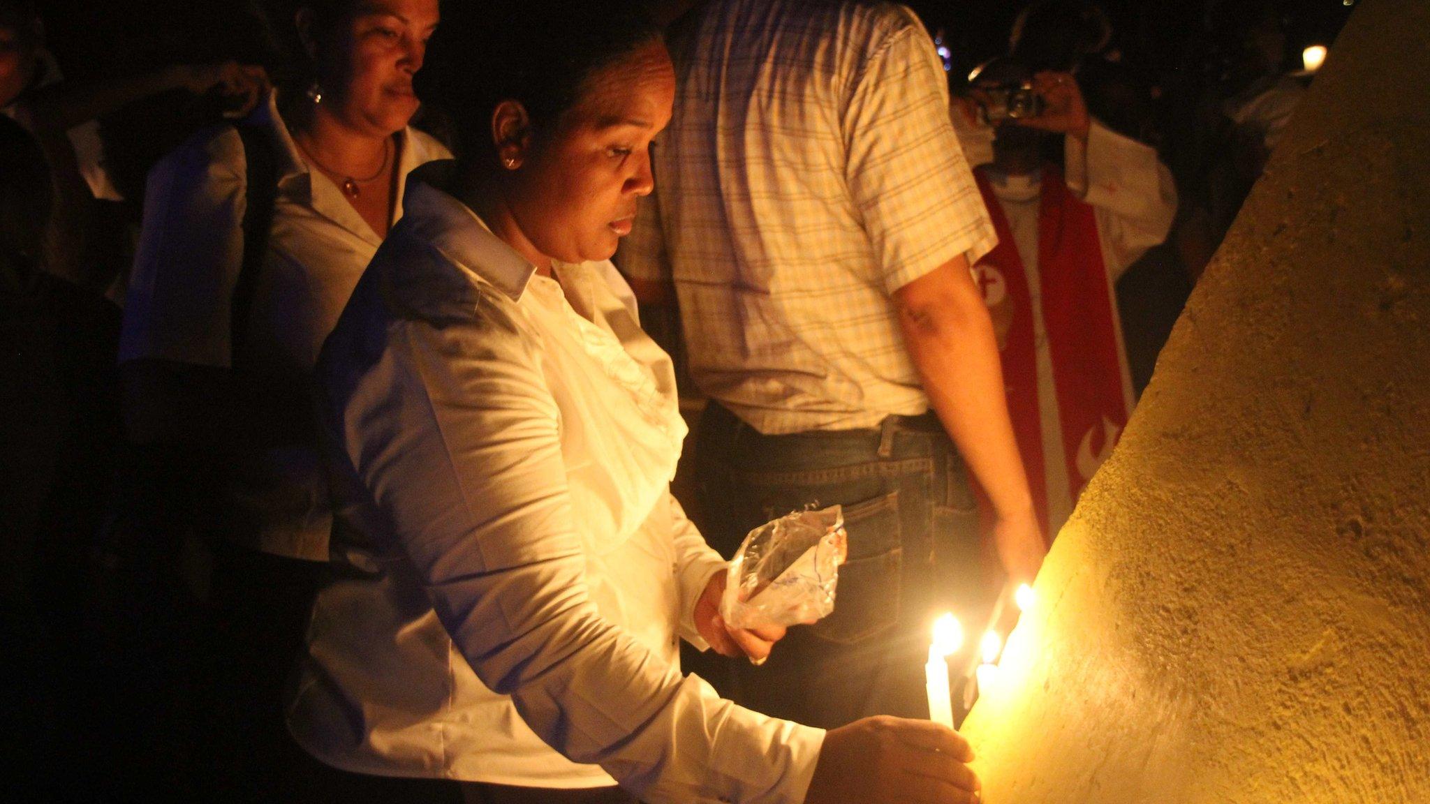 Woman lights candle during events commemorating the 75th anniversary of the massacre