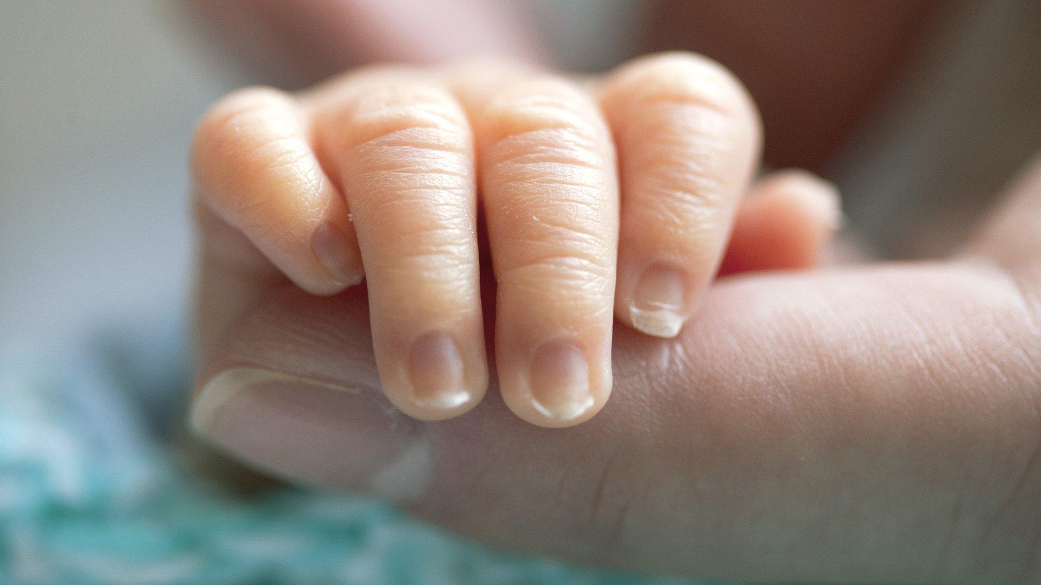 baby gripping adult finger