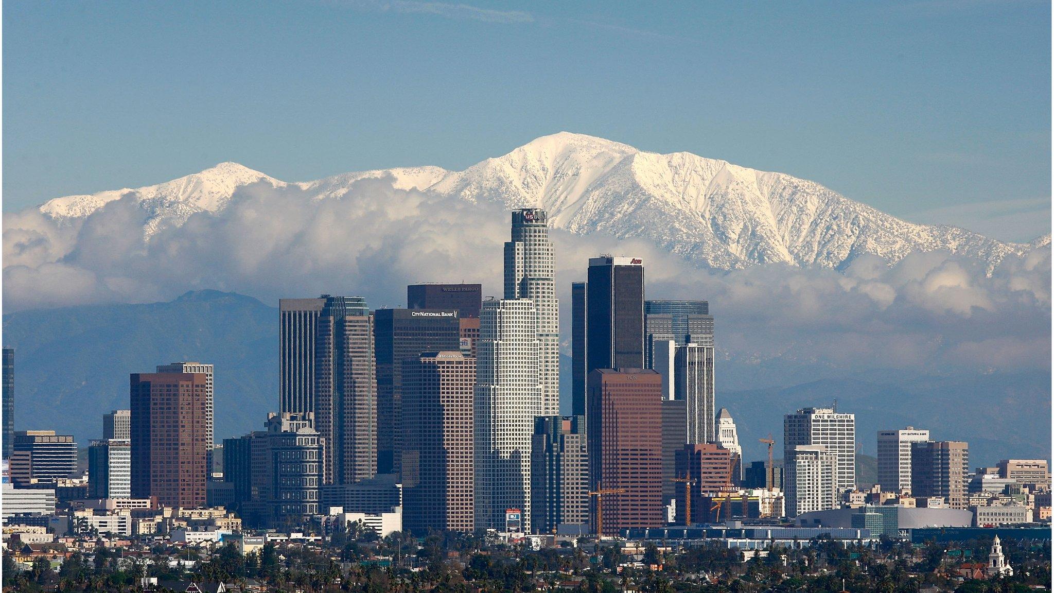 The skyscrapers of Los Angeles climb into a skyline dominated by the snow-covered San Gabriel mountains