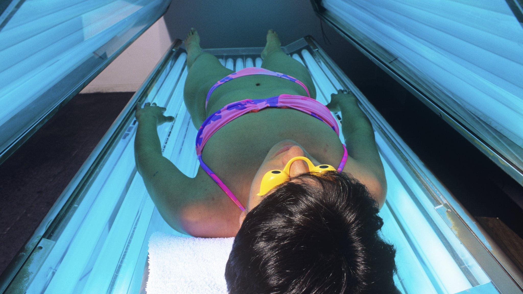 Person sunbathing in a sunbed unit