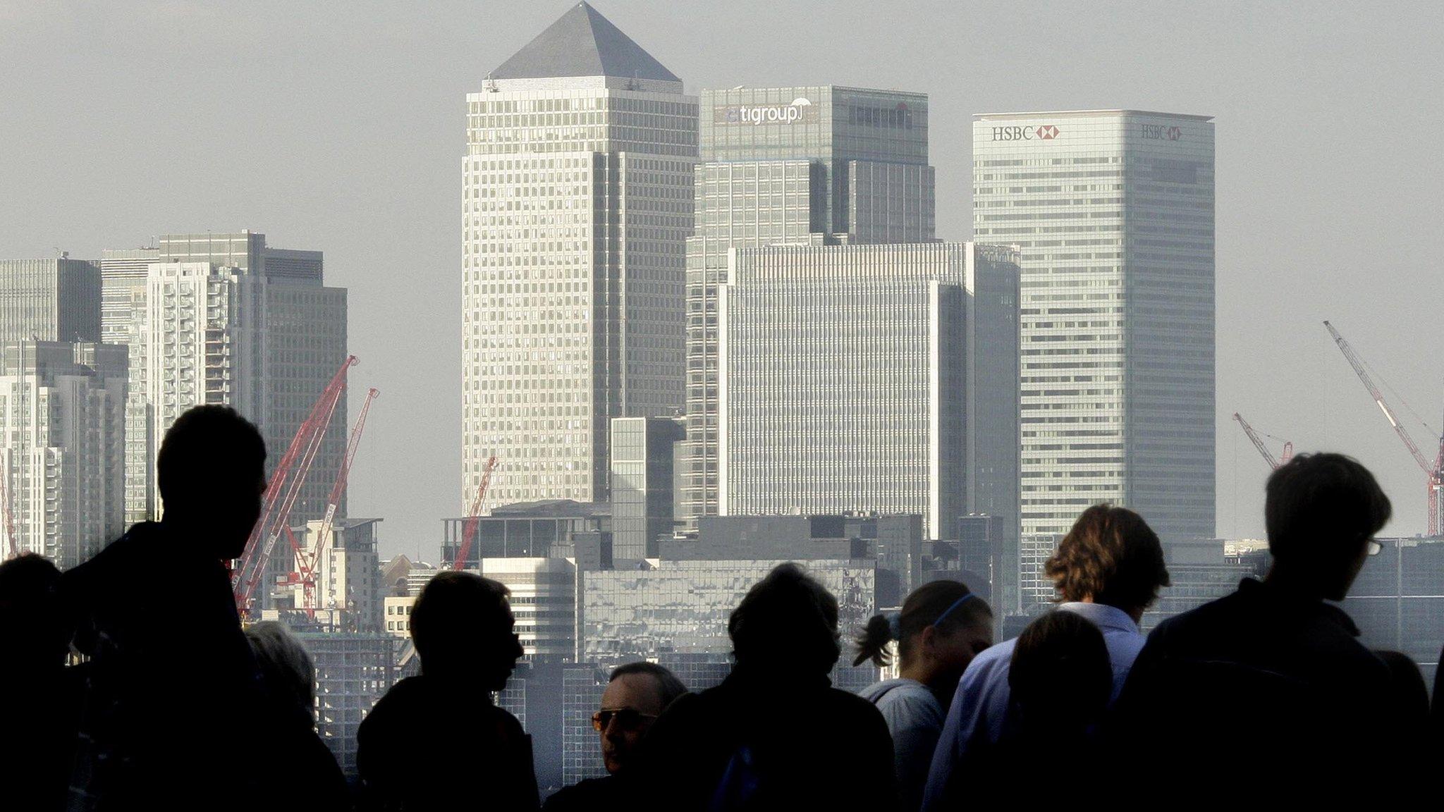 City workers silhouetted in front of the Canary Wharf skyline