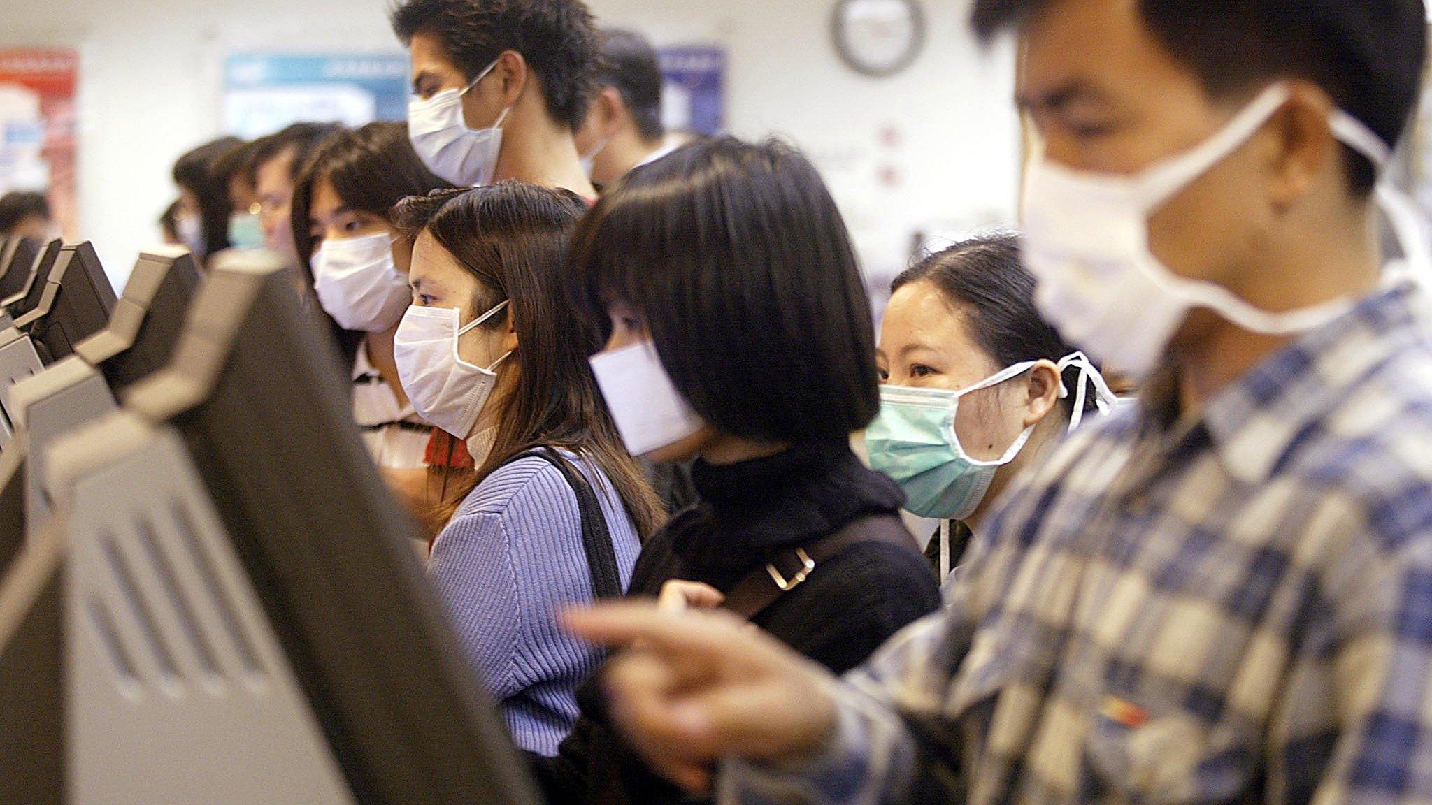 Unemployed people wearing masks look for jobs at a job centre in Hong Kong to protect against a killer outbreak of pneumonia 15 April 2003.