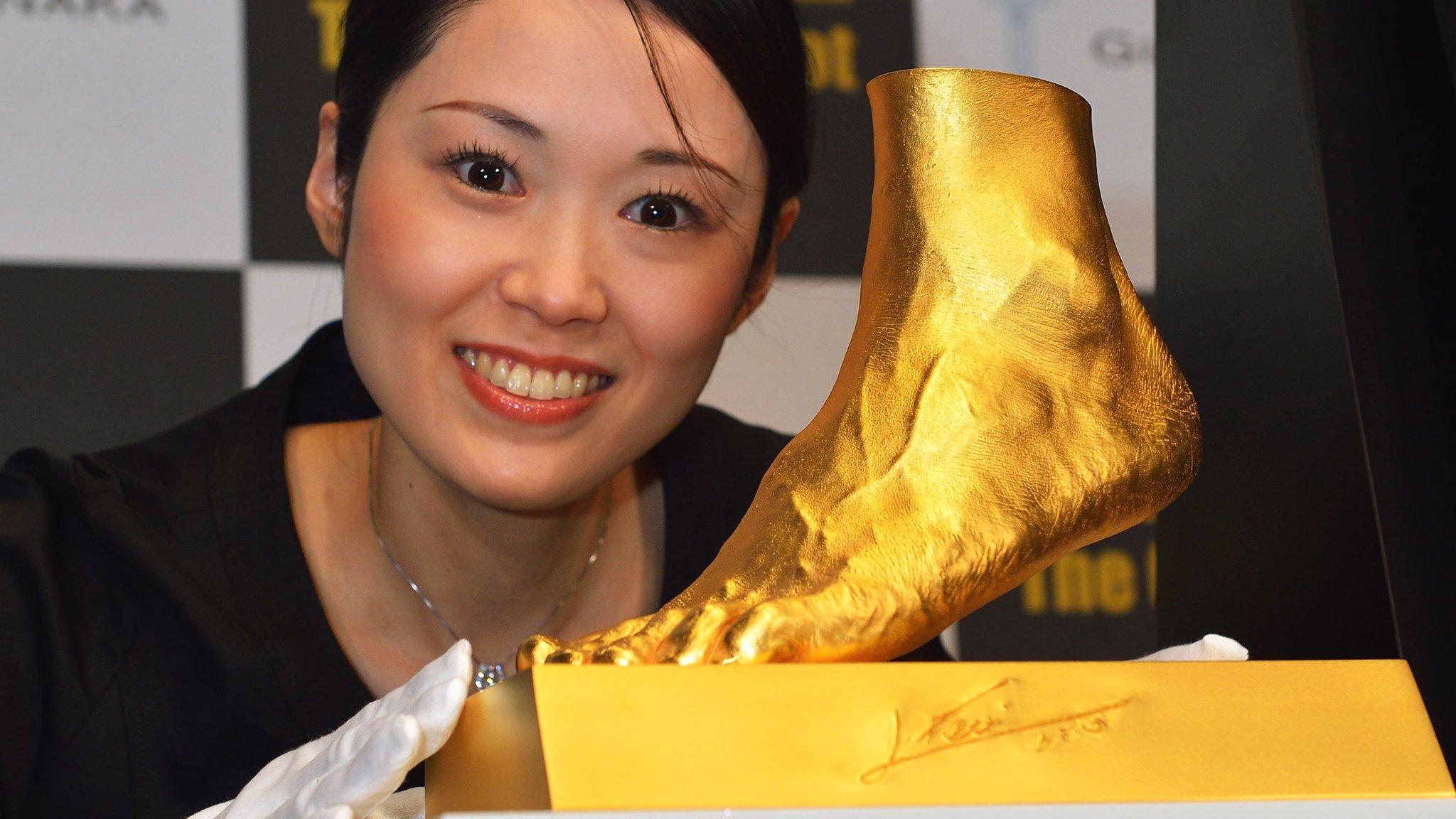 Woman poses with Golden statue of the left foot of Lionel Messi.