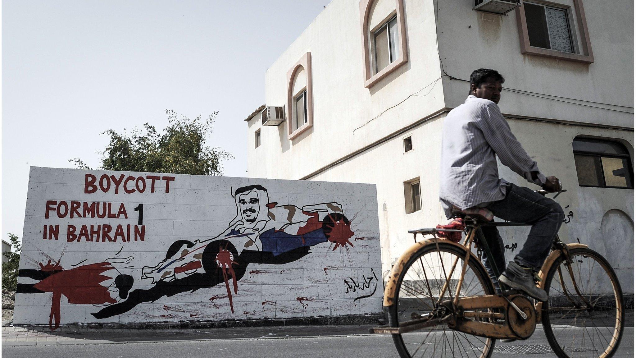 A foreign worker cycles past graffiti against holding the upcoming Formula 1 Grand Prix in Bahrain in the village of Barbar, west of the capital Manama, on March 31, 2013