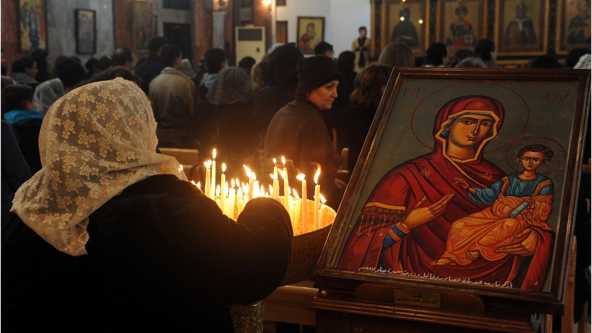 A Syrian woman lights candles as she attends Mass at the Mar Elias (St Elijah) Orthodox church in Bab Touma, Damascus (24 December 2012)