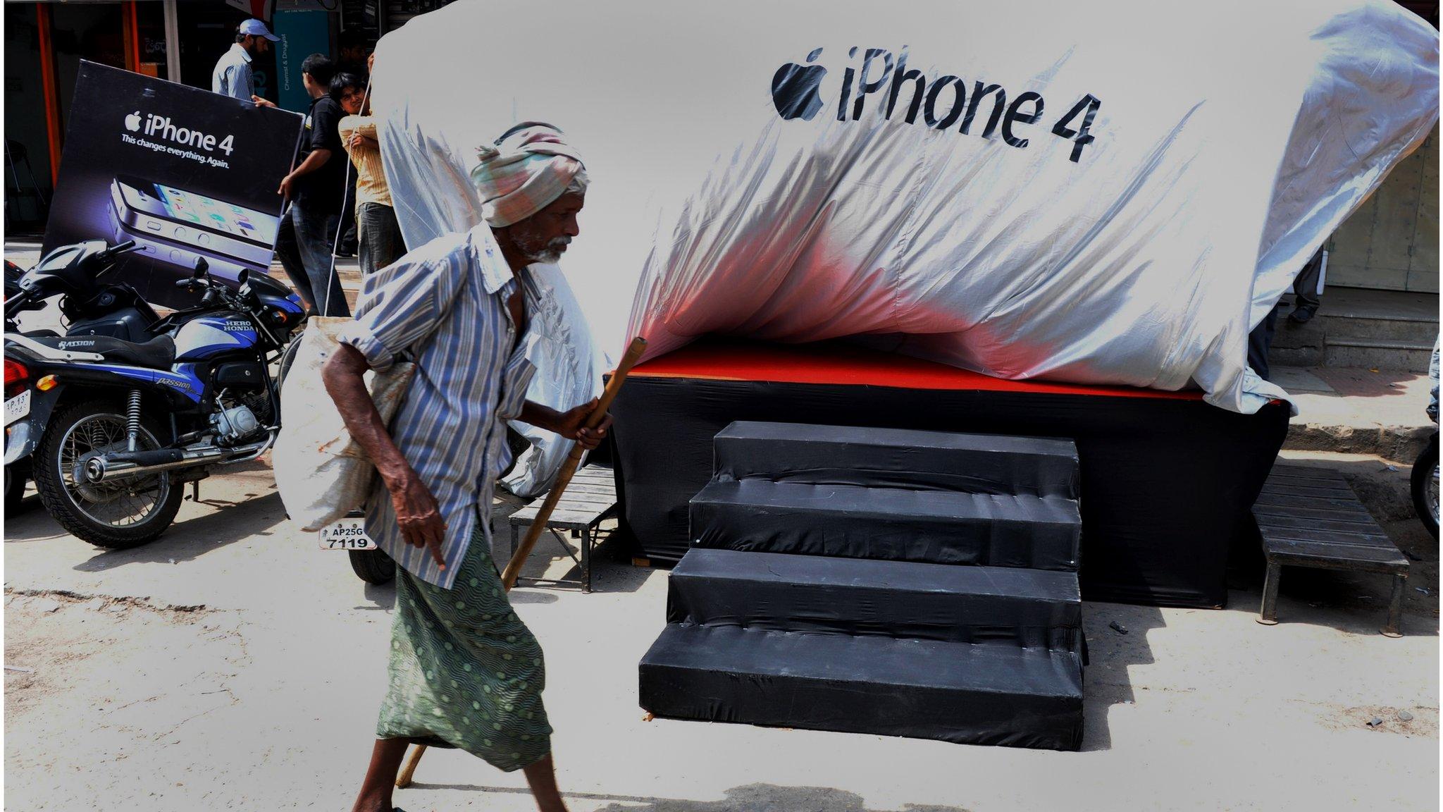 An Indian man walks past the logo of the iPhone 4 during its launch by provider Aircel in Hyderabad