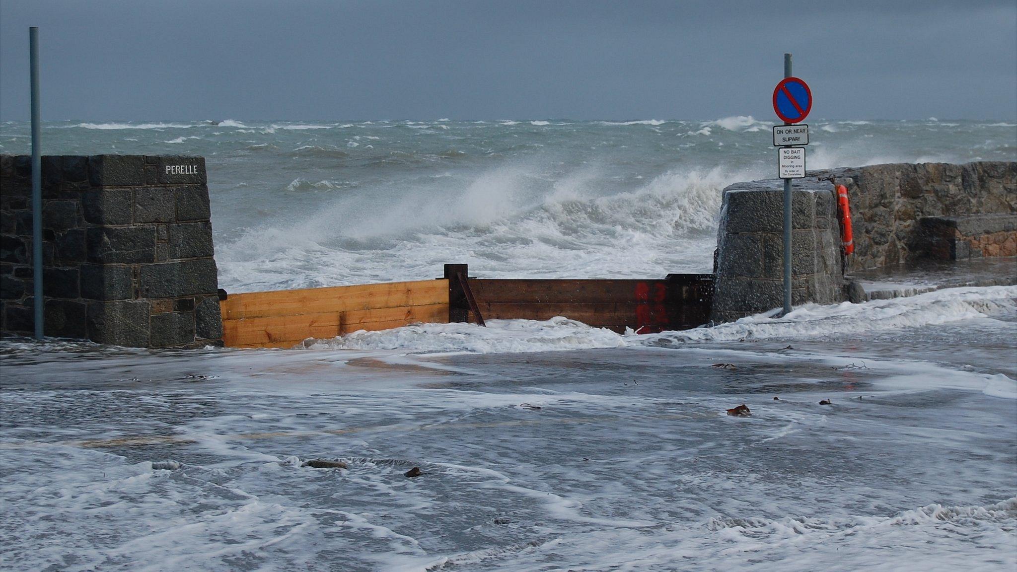 Waves crash over the sea wall at Perelle