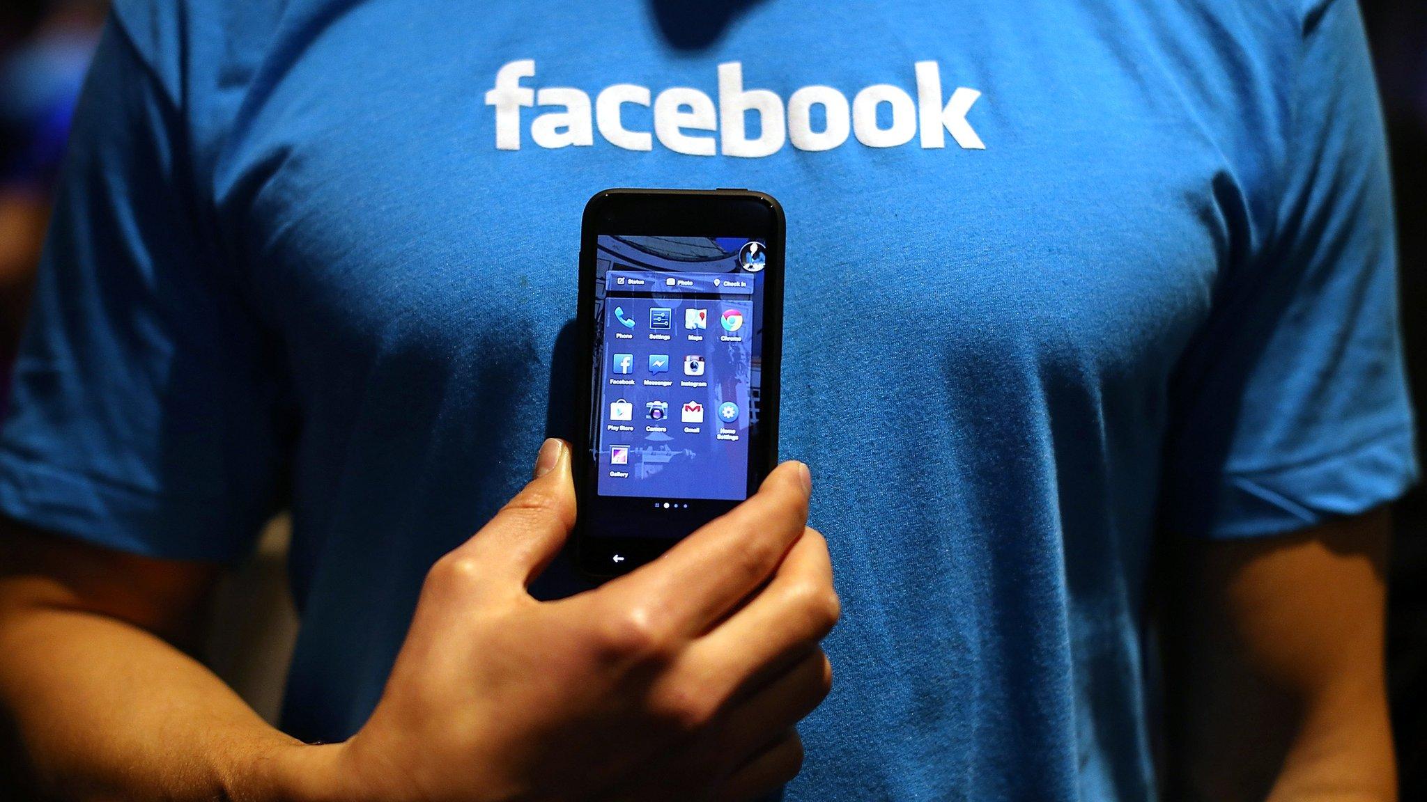 Facebook employee holds a mobile phone