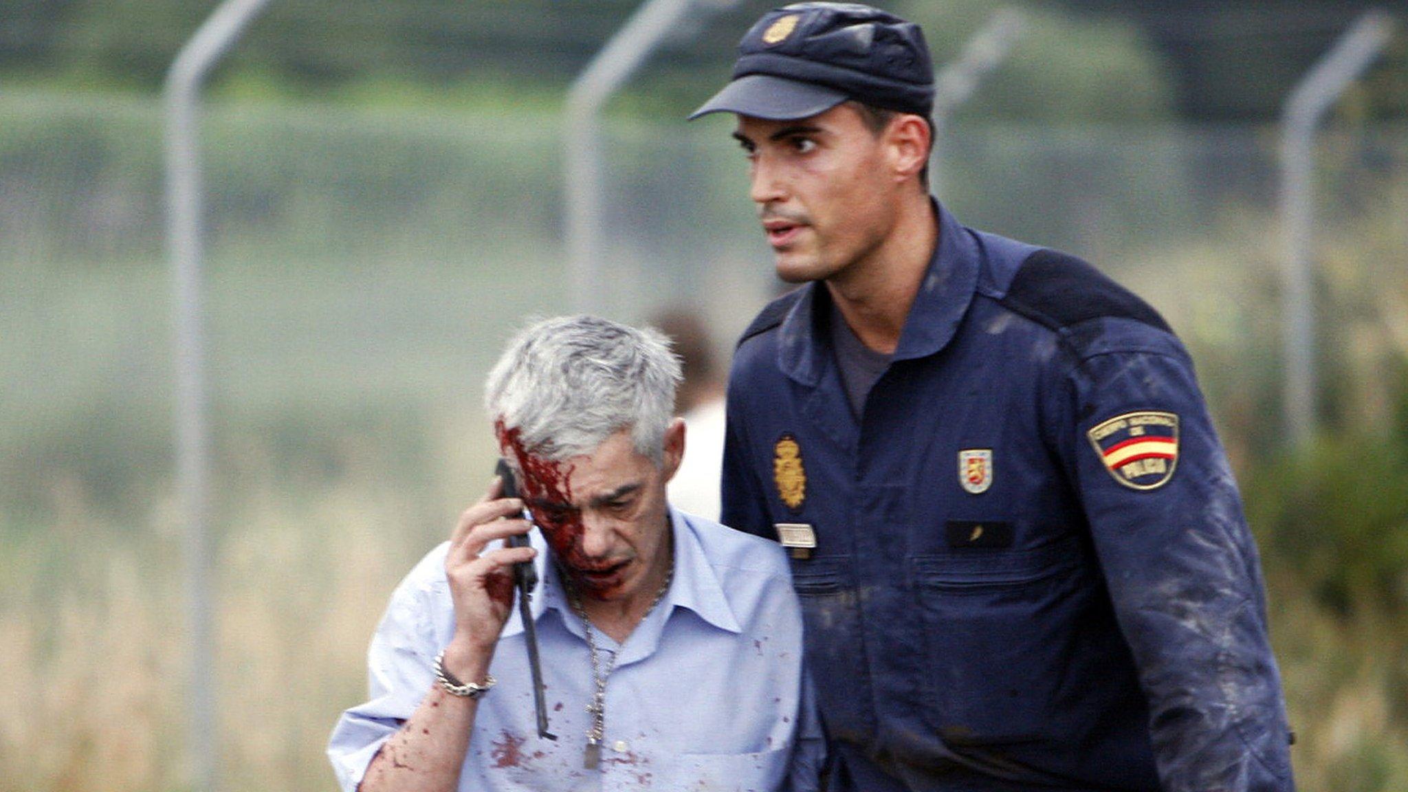 Injured train driver Francisco Jose Garzon helped away by policeman. 24 July 2013