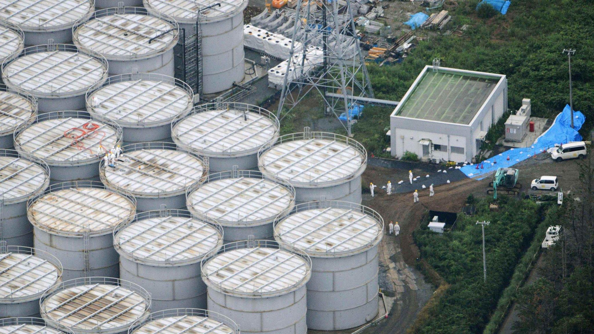 Enormous water storage tanks dwarf the workers stood on top of one of them