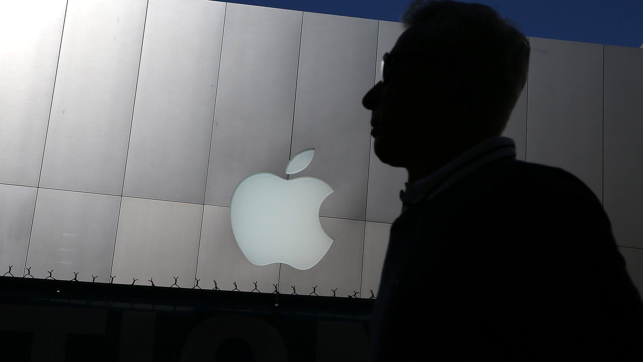 A man walking past an Apple logo