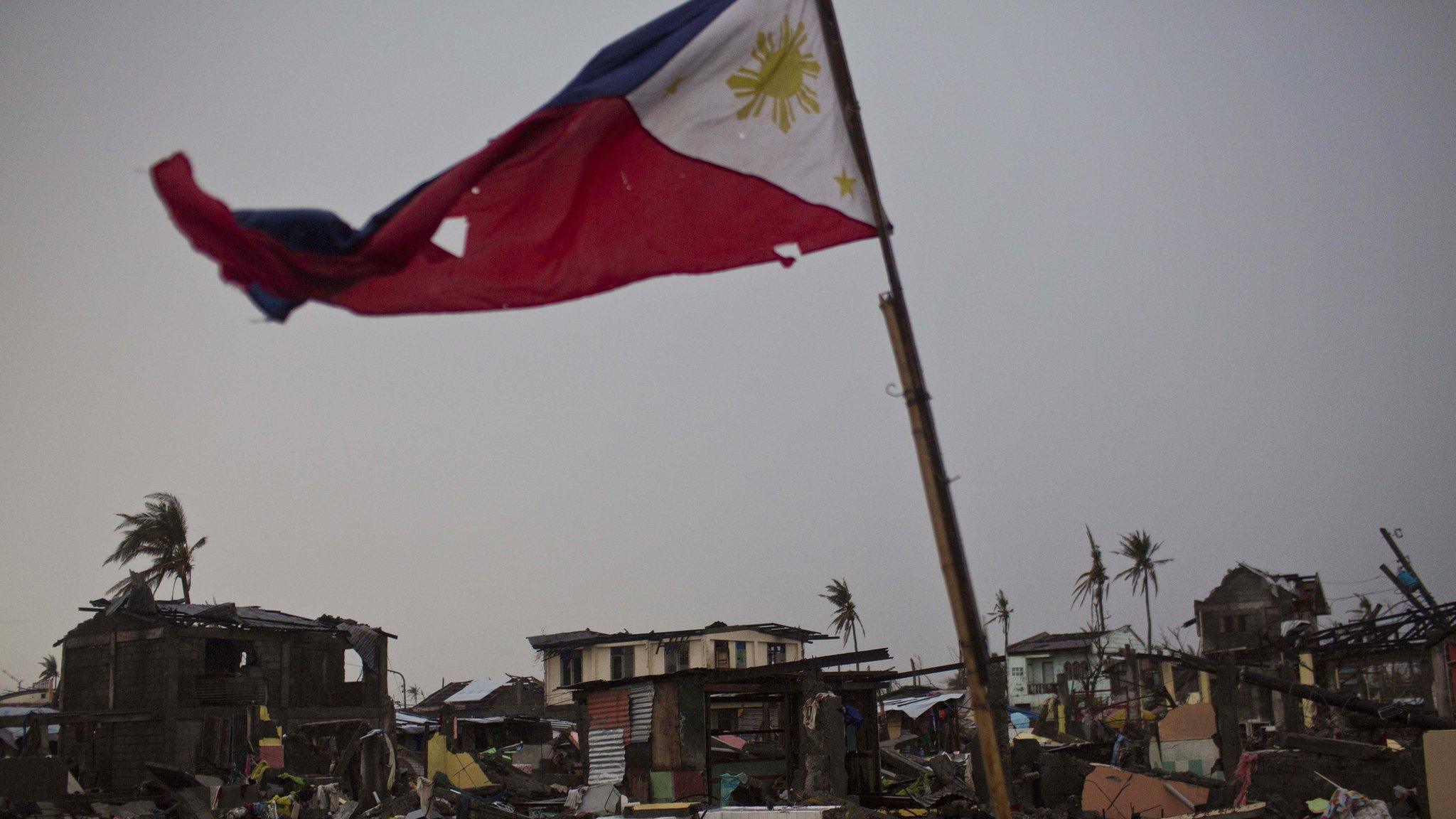 A flag of the Philippines flies over a destroyed neighbourhood in Tacloban, Philippines (22 Nov. 2013)