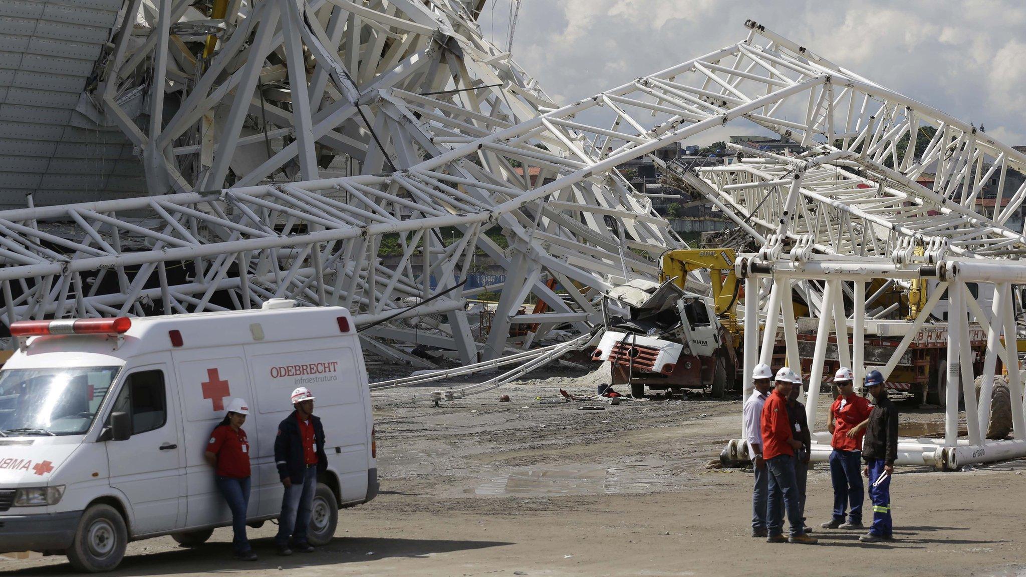 Workers look on at the Arena Corinthians after the crane collapse