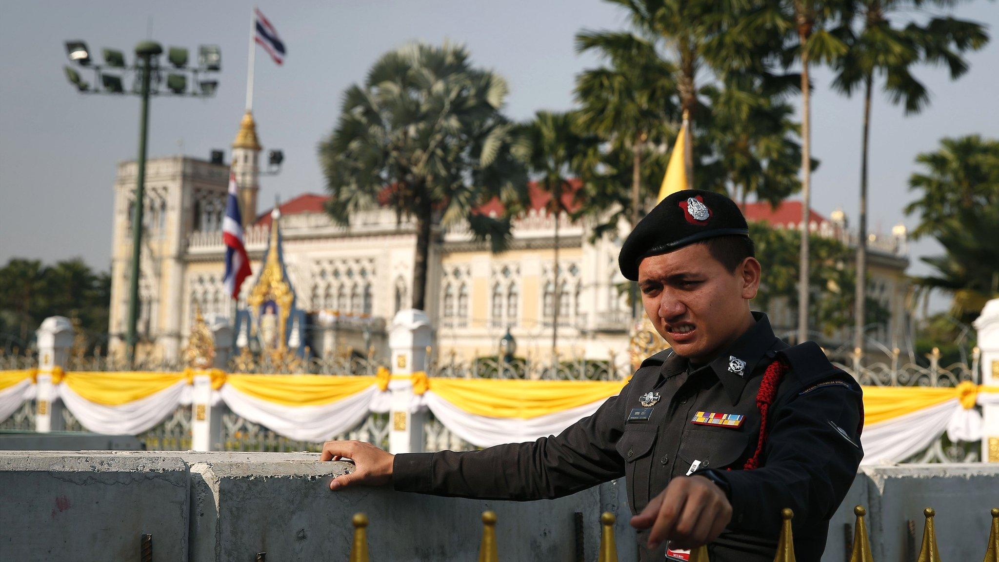 A Thai policeman stands next to concrete barricades outside the gates of the prime minister's office, known as Government House, in Bangkok, Thailand