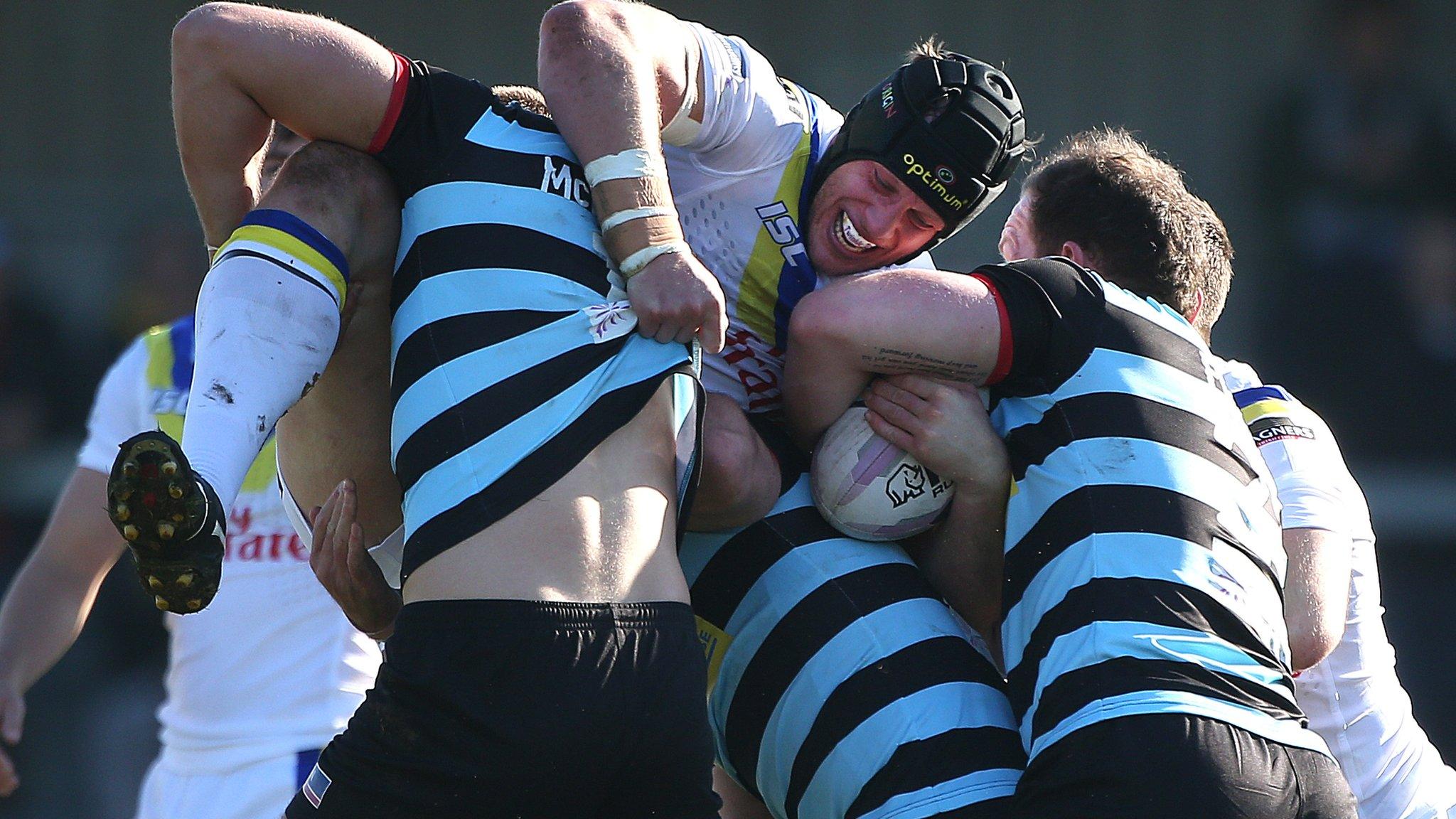 Chris Hill of Warrington is held by the Broncos defence