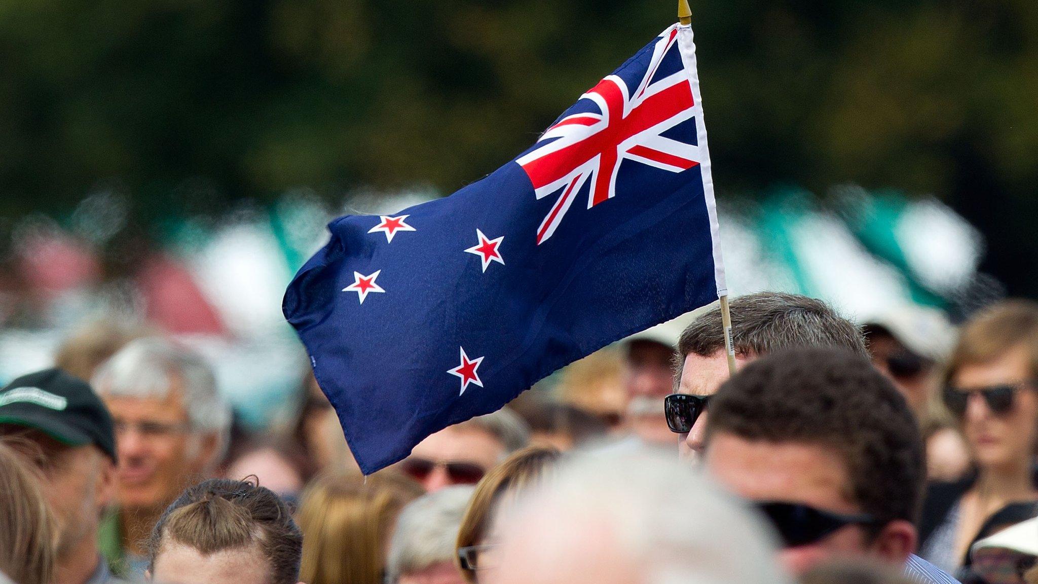 A man holds a New Zealand flag at a ceremony in Christchurch on 22 February 2012