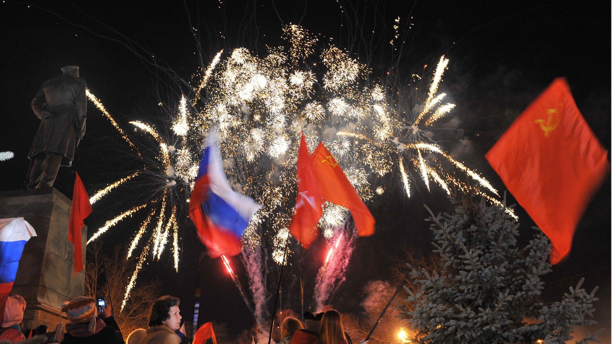 People wave Russian and Soviet flags as they look at fireworks in the Crimean city of Sevastopol (21 March 2014)