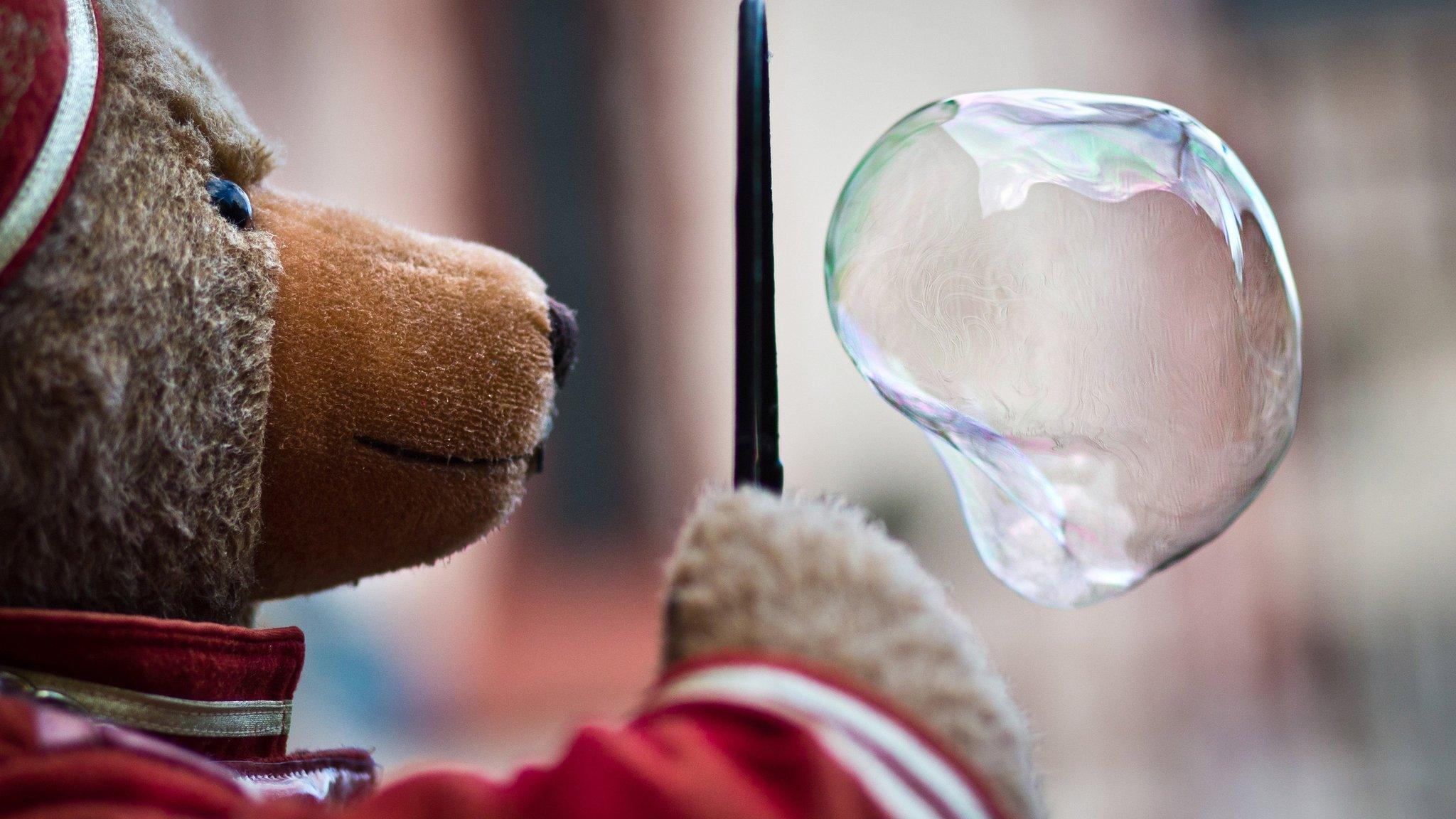 A plush teddy makes a soap bubble