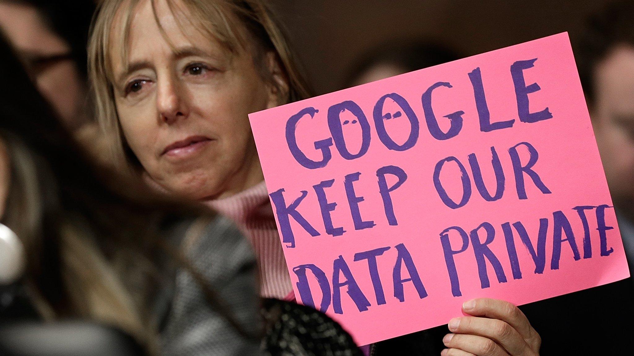 Woman displays a sign at a Senate hearing into Google activity