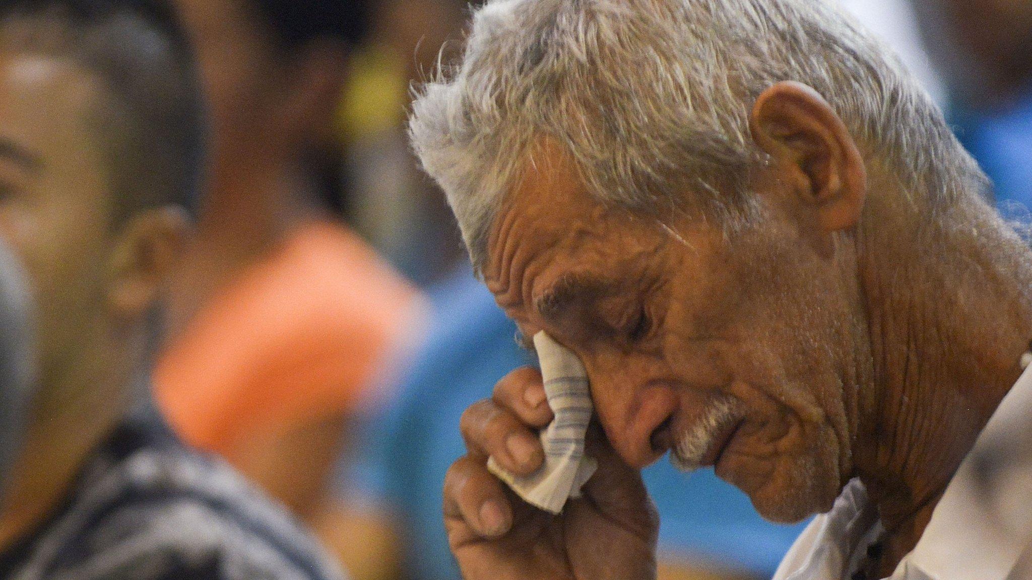 Miguel Montoya cries next to the urn with the remains of his relative disappeared during the Colombian conflict in a ceremony in Medellin, on 7 February , 2014.