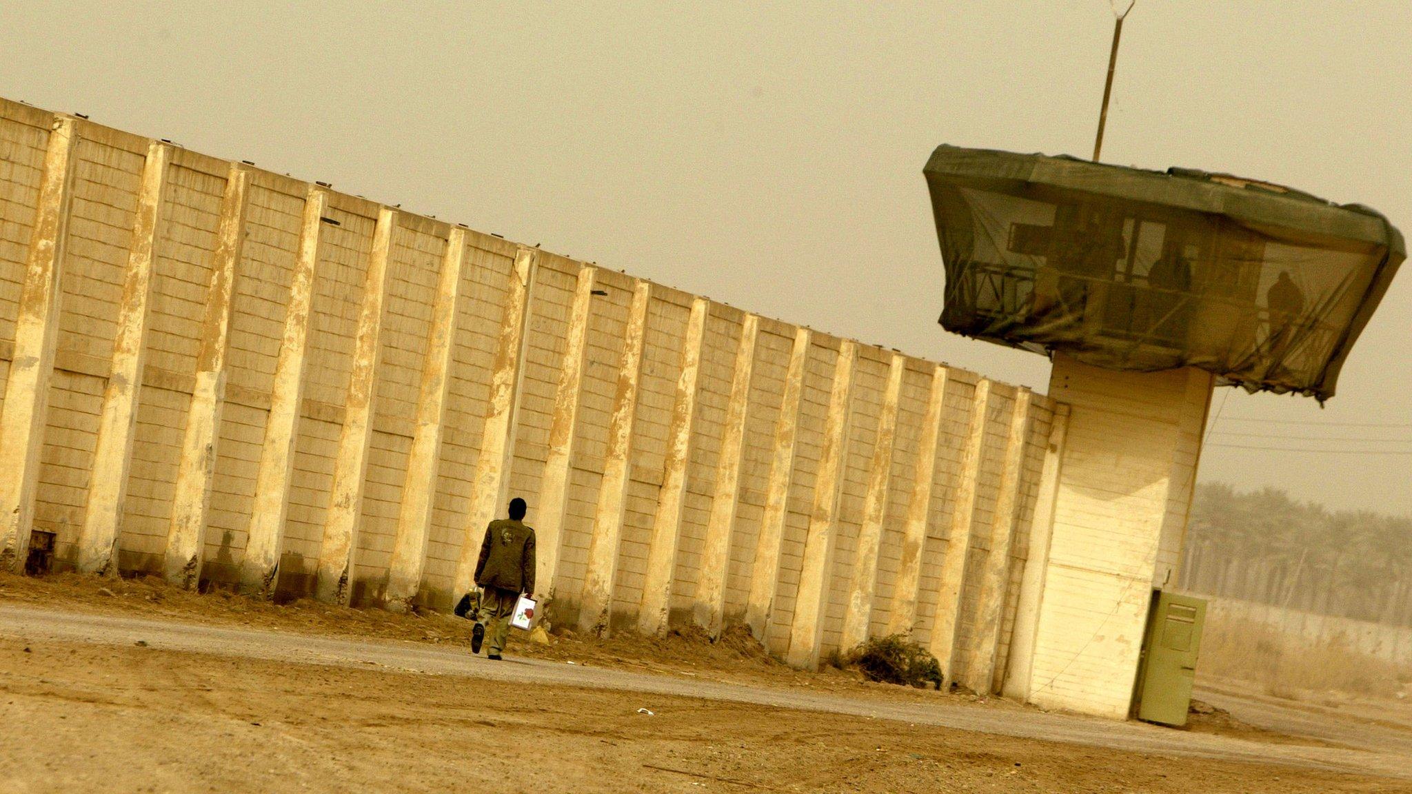 A man walks past Abu Ghraib prison (2009)