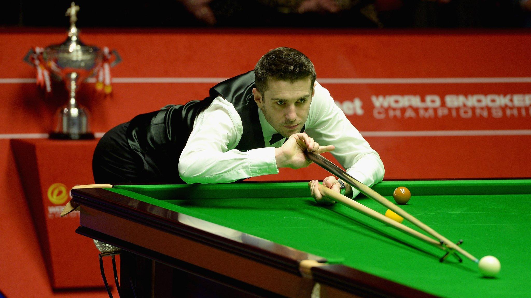 Mark Selby pots as the trophy awaits behind him