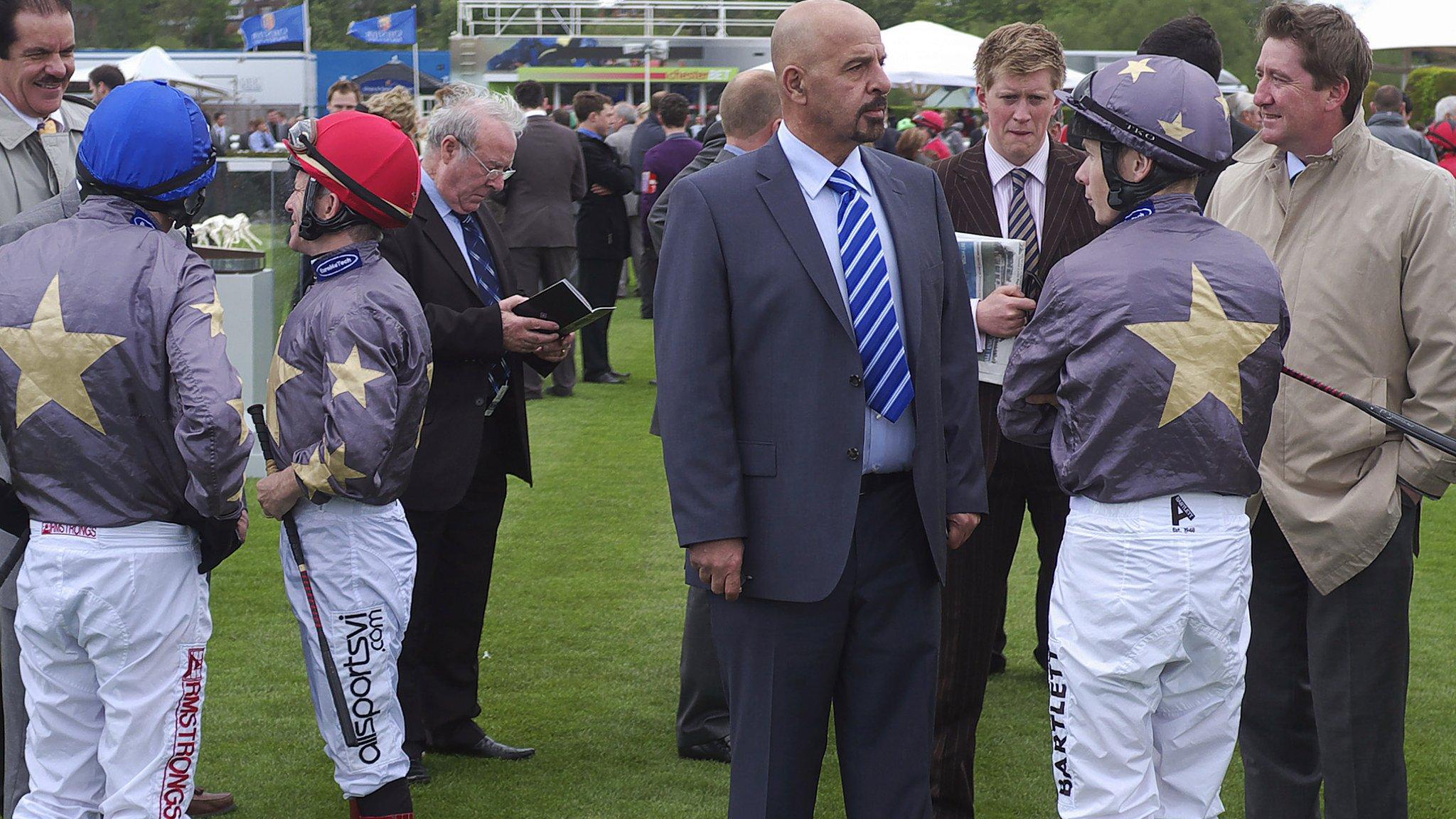 Dr Marwan Koukash stands with three jockeys who wear his colours