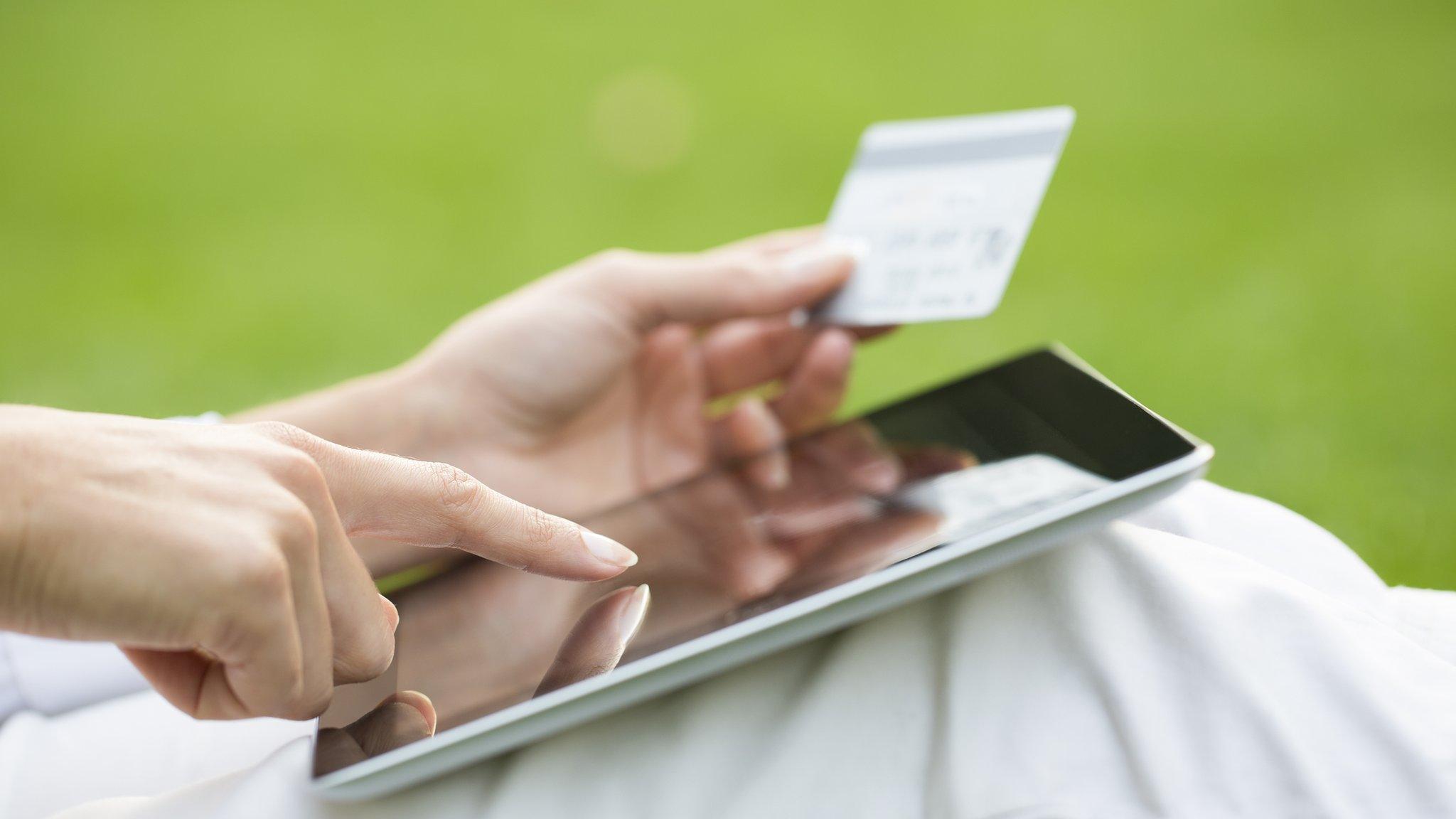 Woman's hands holding a credit card and using tablet pc