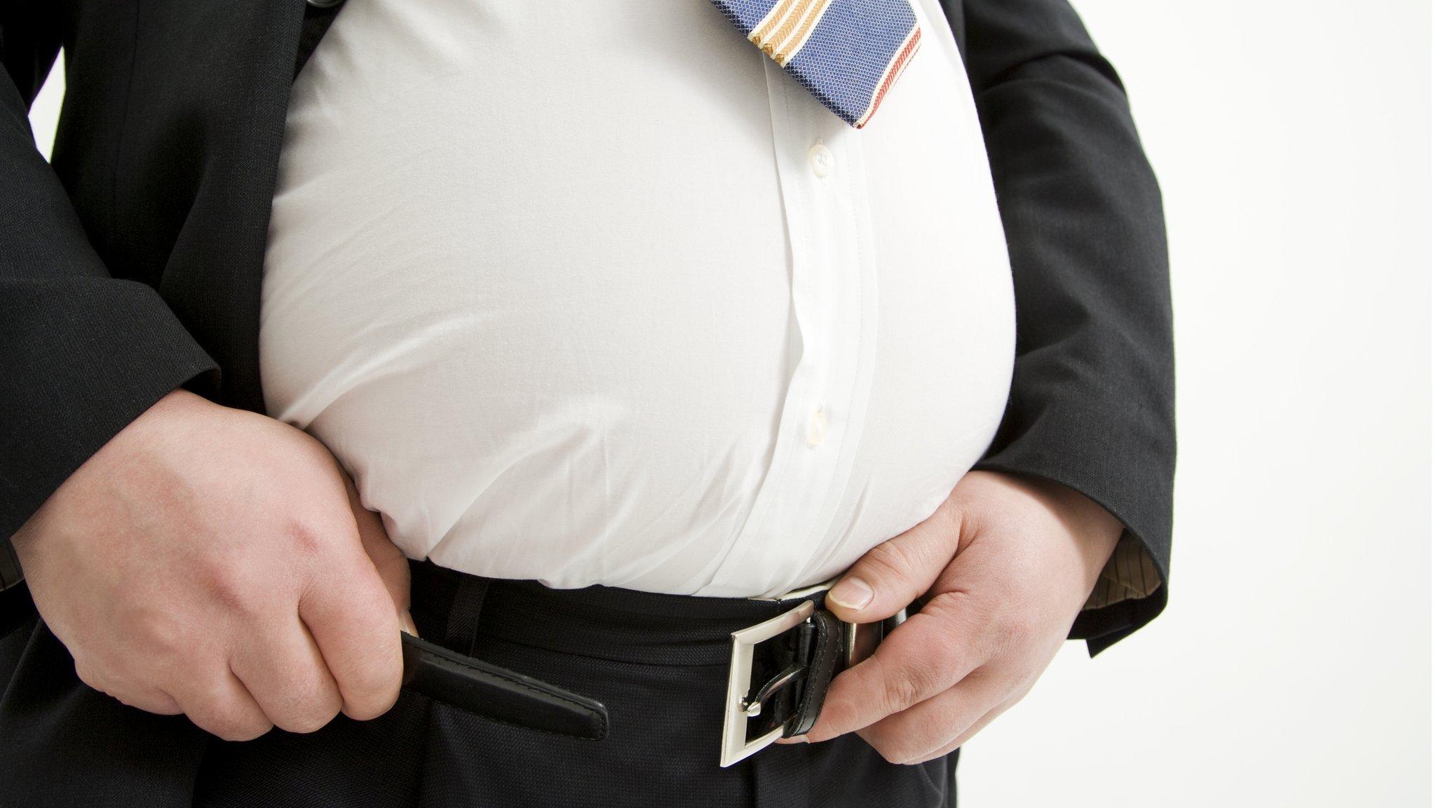 Obese man struggling with belt