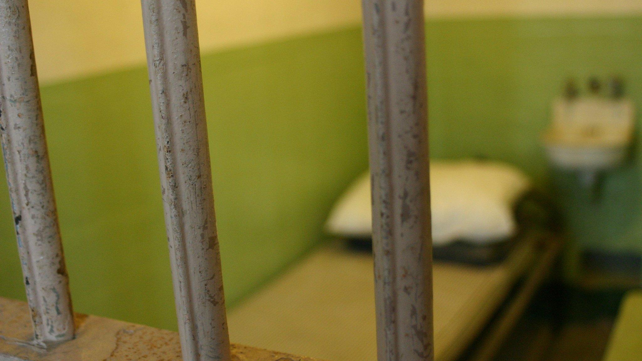 A bed seen through cell bars